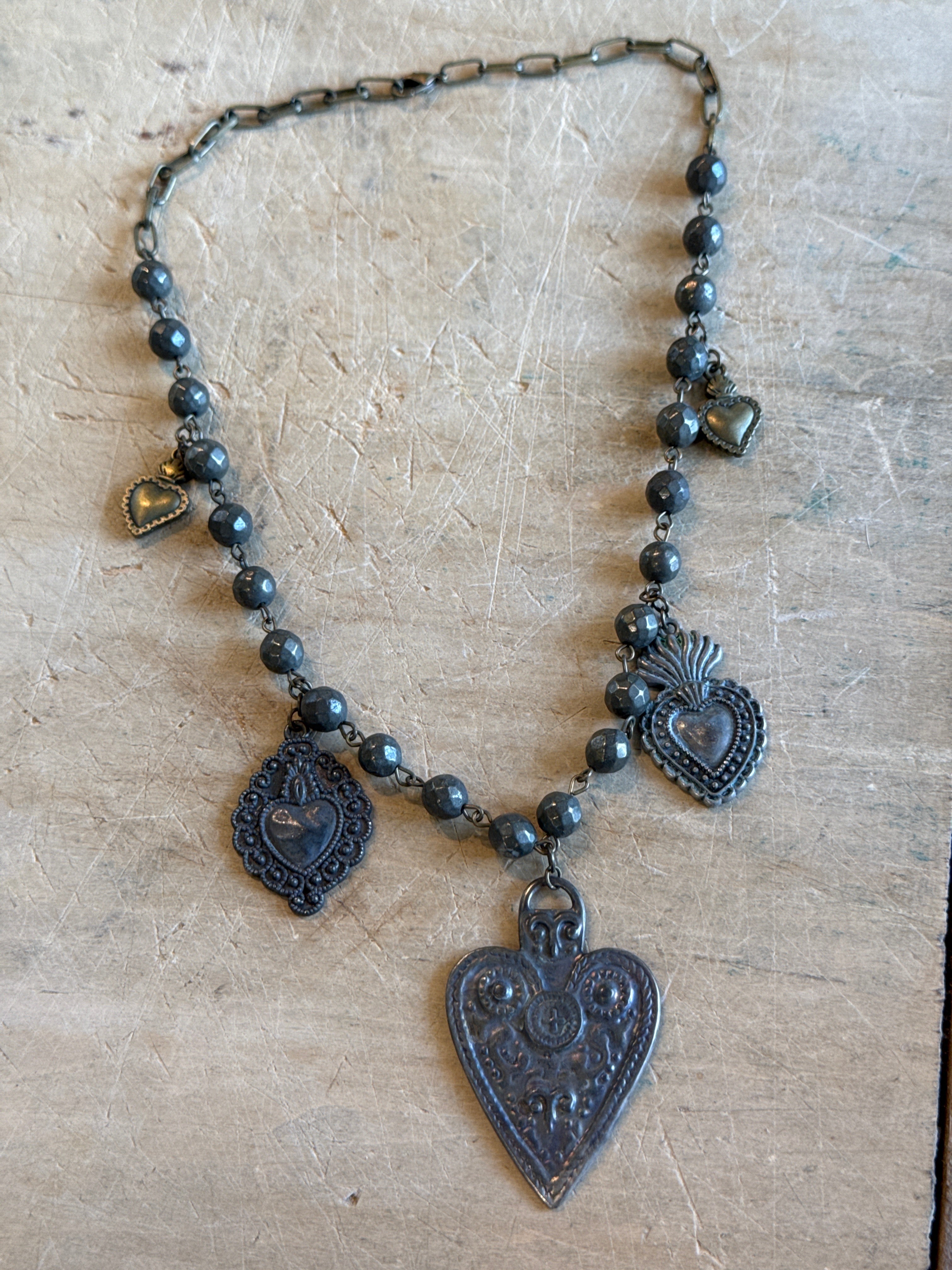 Decorative necklace with heart-shaped pendants on a textured surface