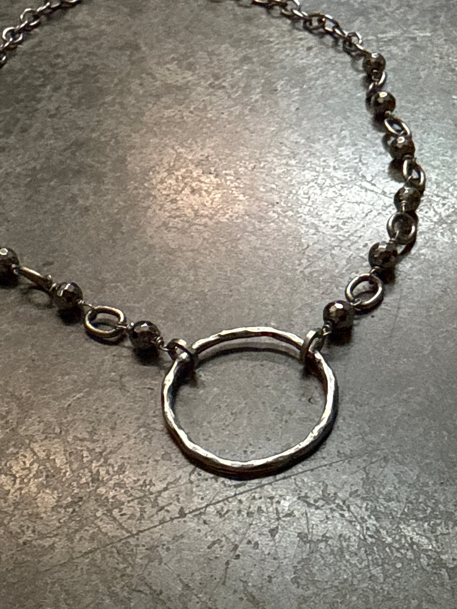 Close-up of a silver ring and chain on a textured gray surface