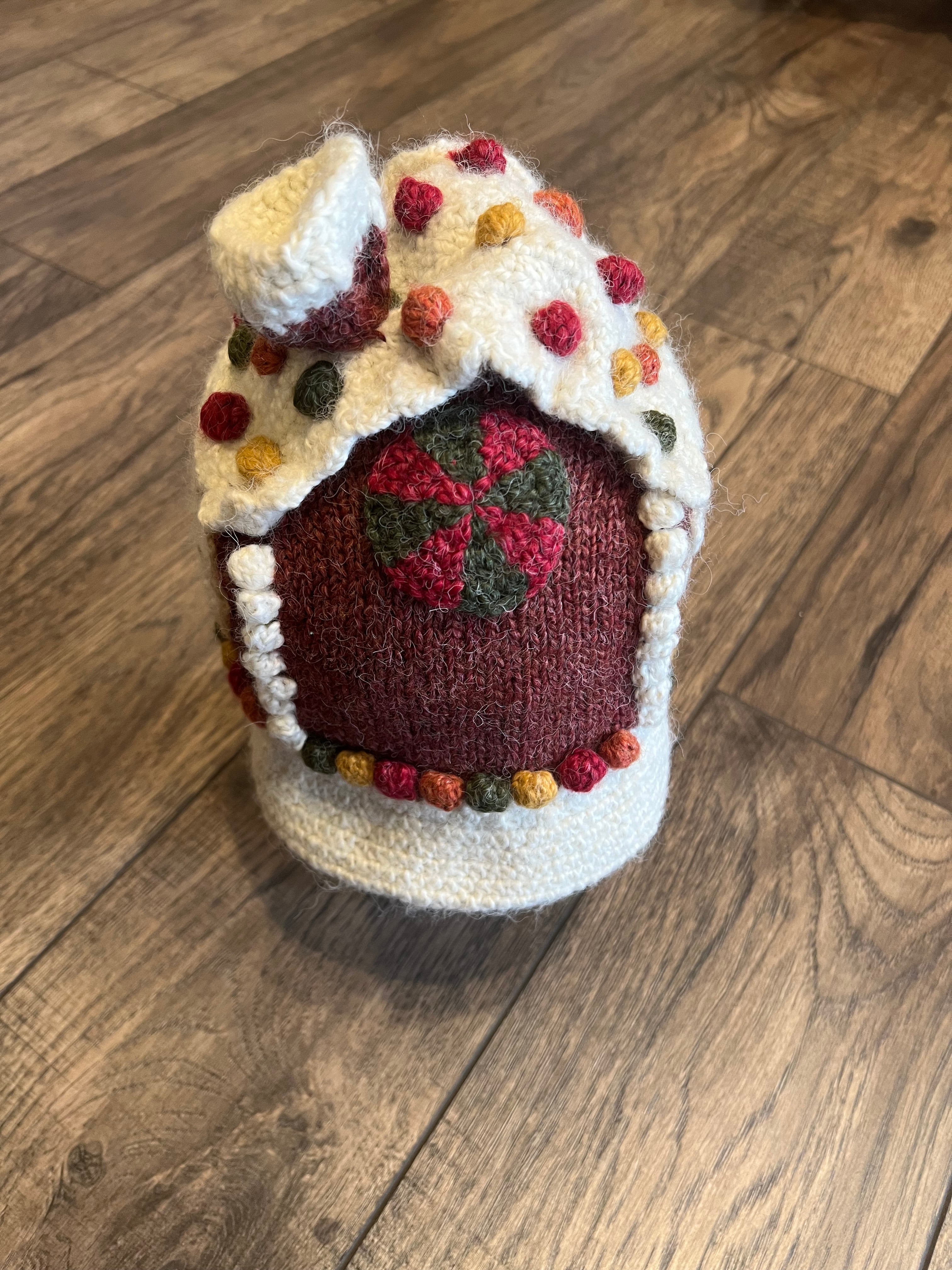 Knitted Gingerbread house with decorative patterns on a wooden floor