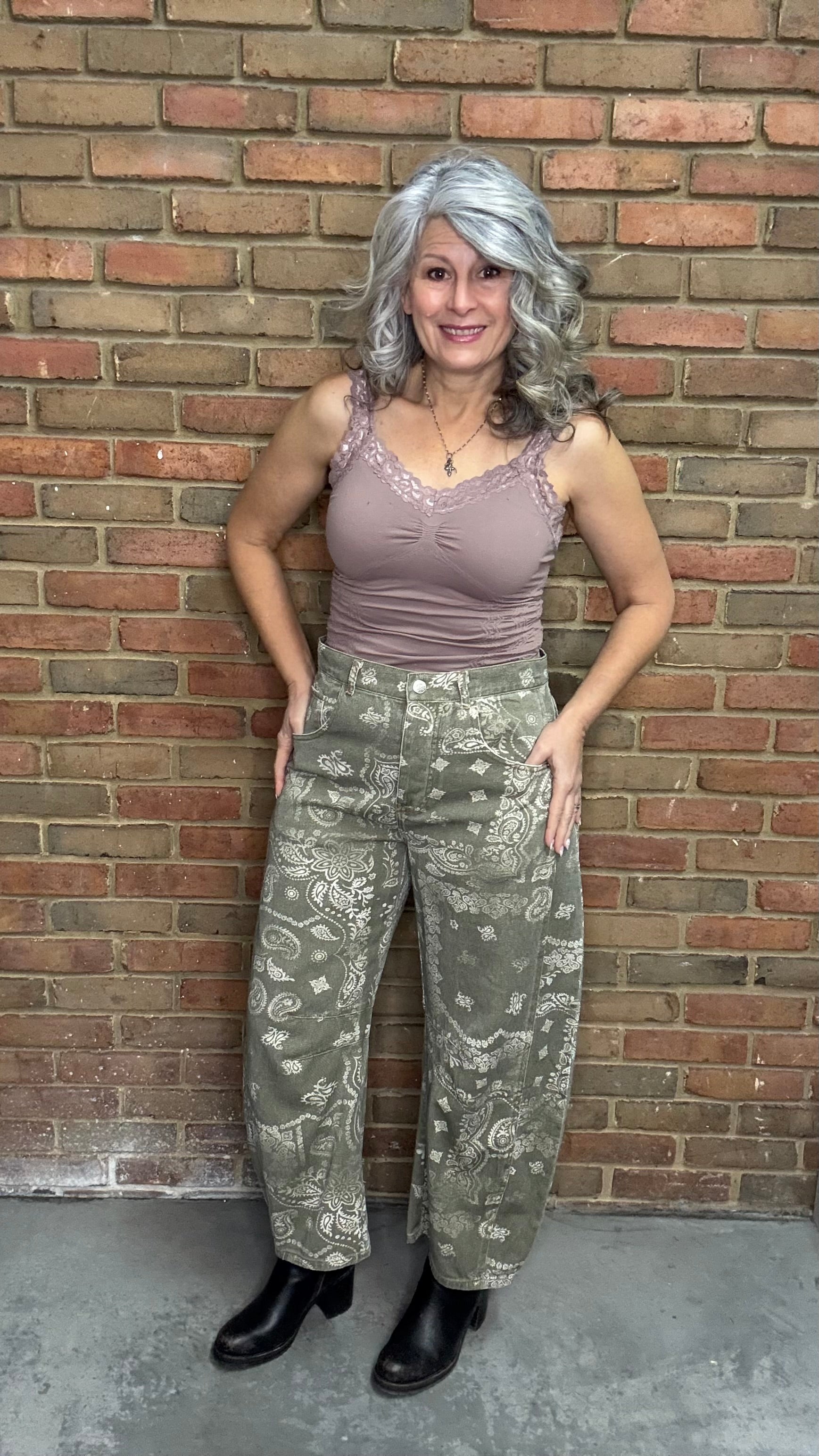 Woman wearing Lace Camisole and the Paisley Print Jean standing against a brick wall.
