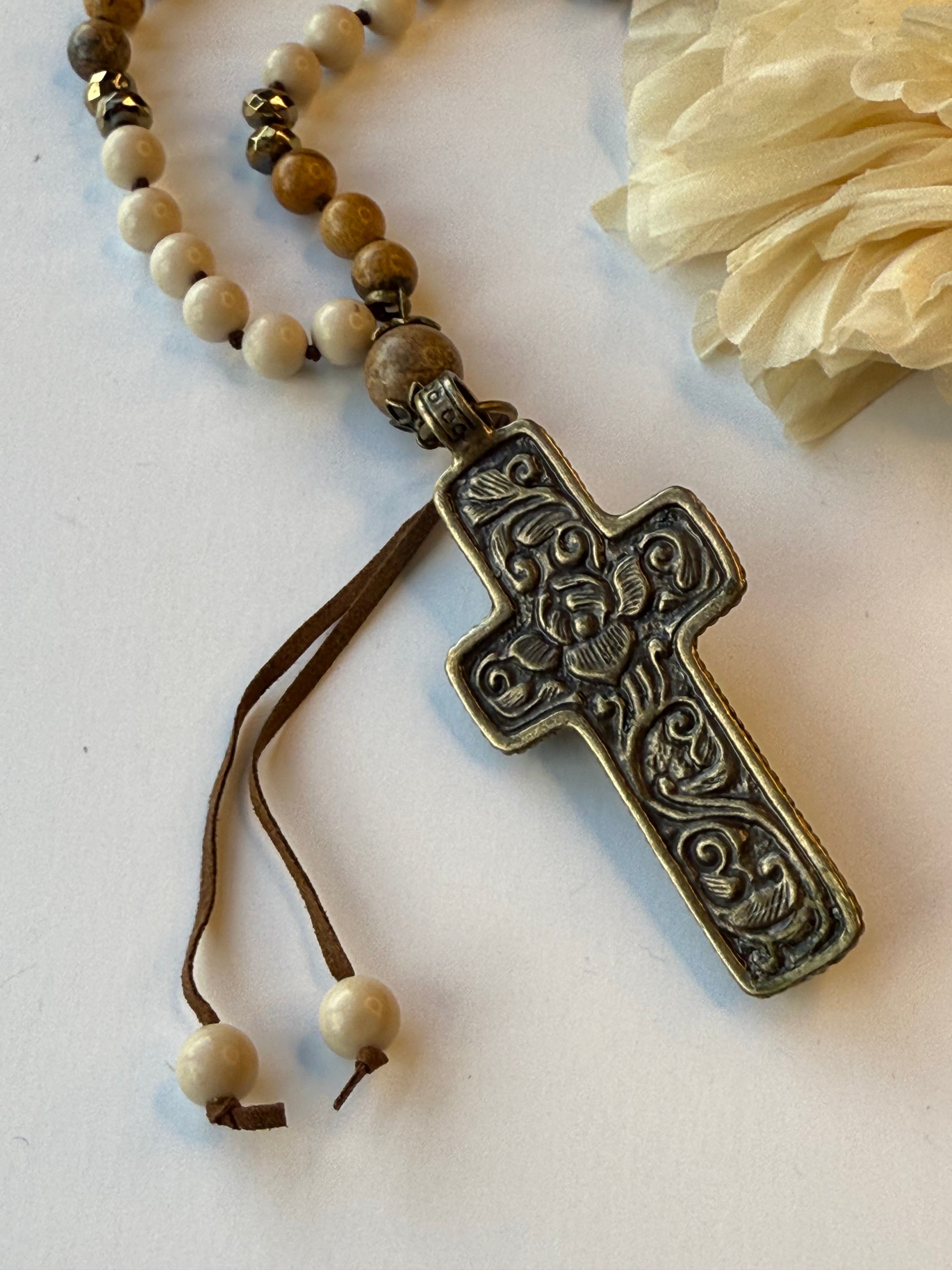 Decorative cross necklace with beads on a light background