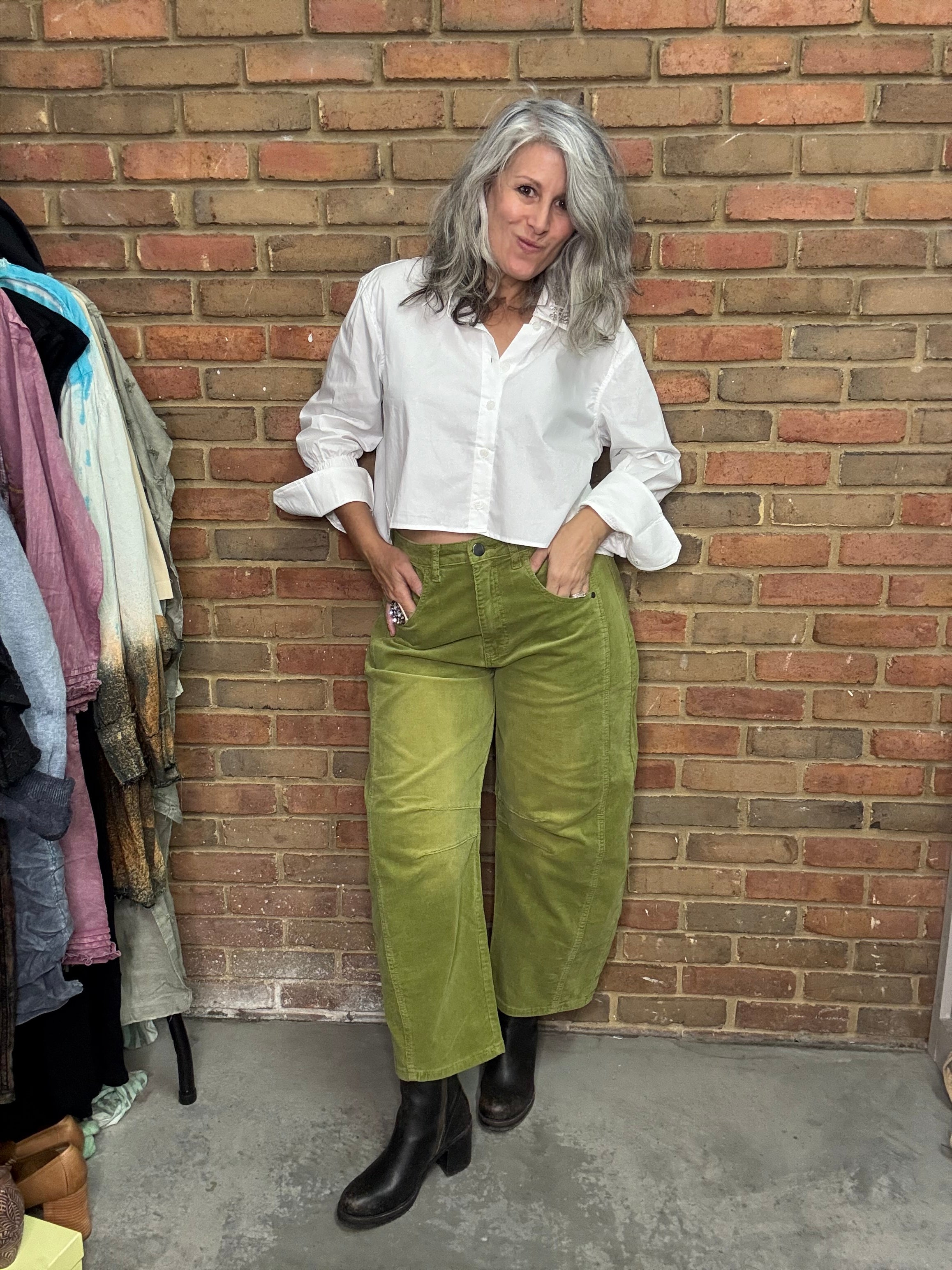 Person wearing a white shirt and green pants on a brick floor