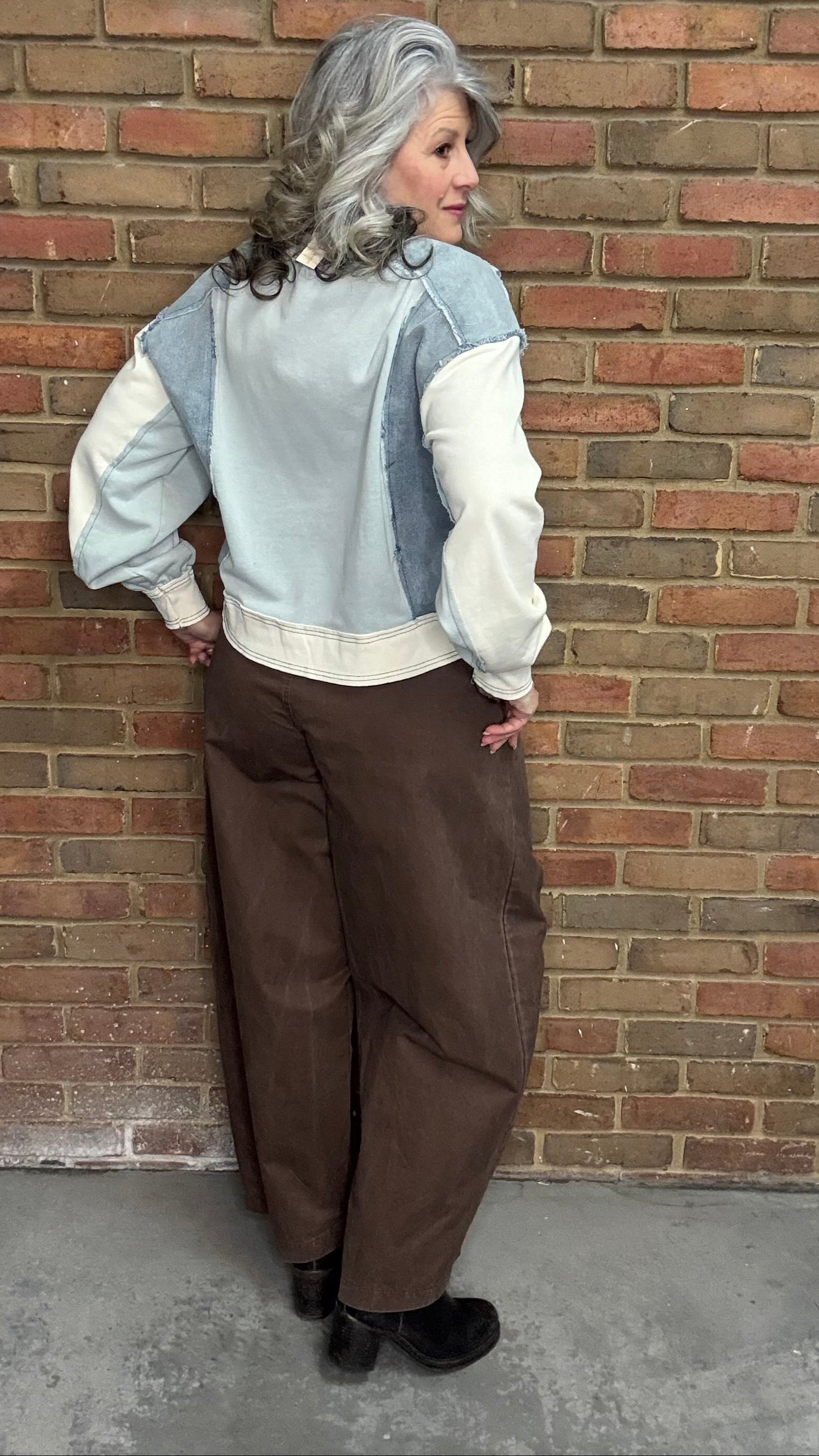 Person wearing the blue Color Block Pull on with the Brown Pull On Barrel Pants, standing against a brick wall.