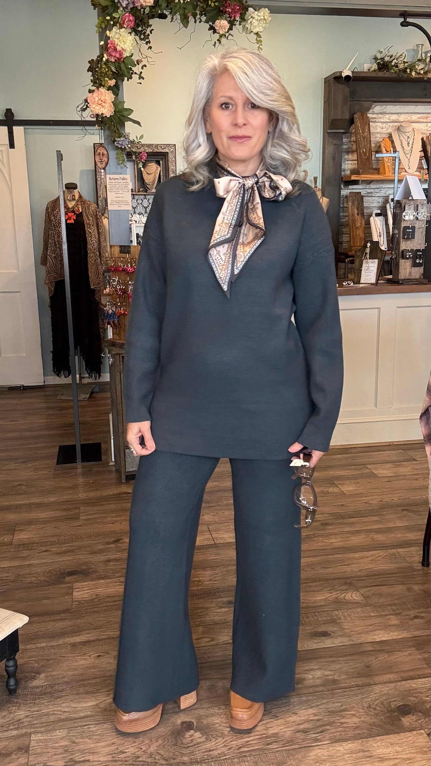 Woman in a denim color sweater outfit with a patterned scarf standing in a store.