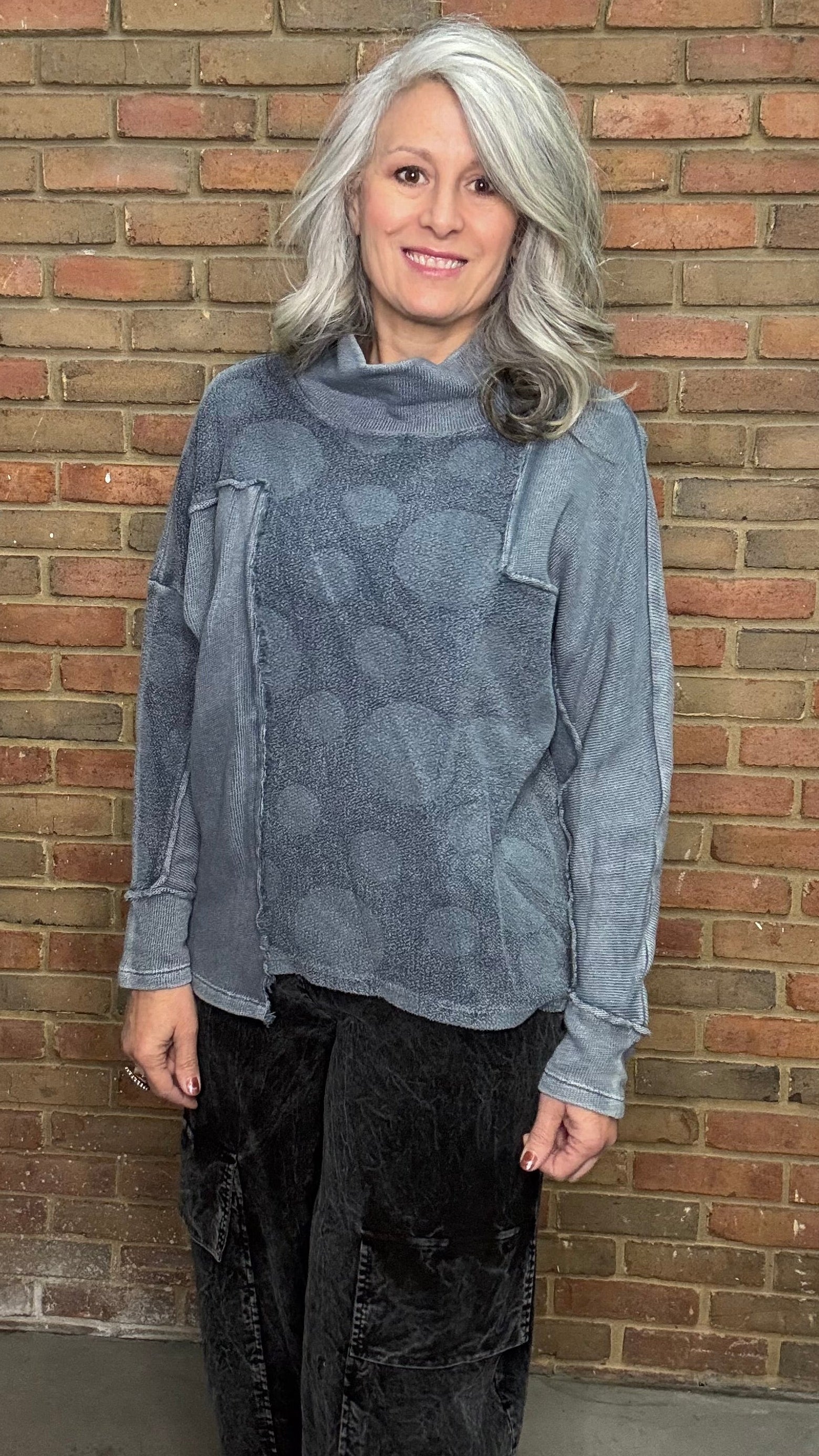 Person wearing the Adelia Top Chalice and the Karlene Corduroy Pants standing against a brick wall.