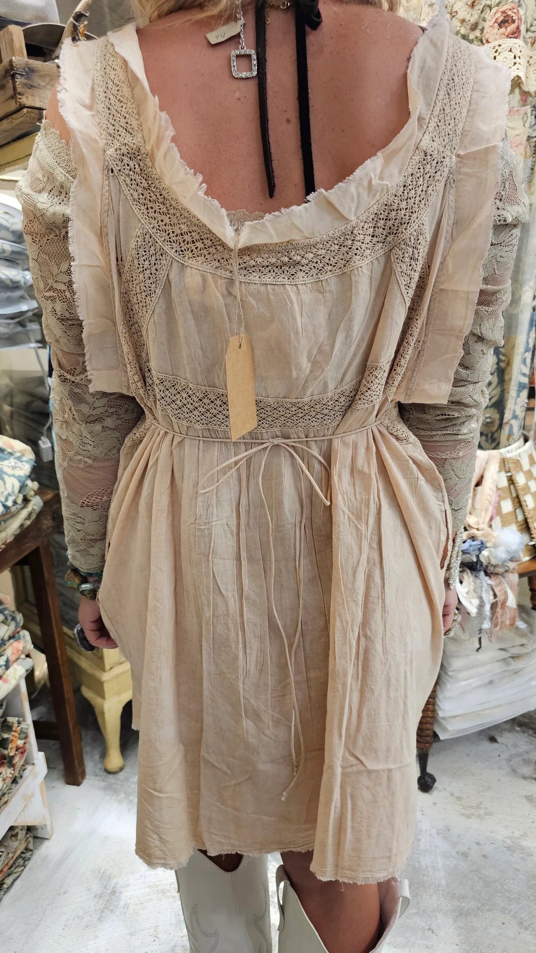 Beige lace dress with a tag in a store setting