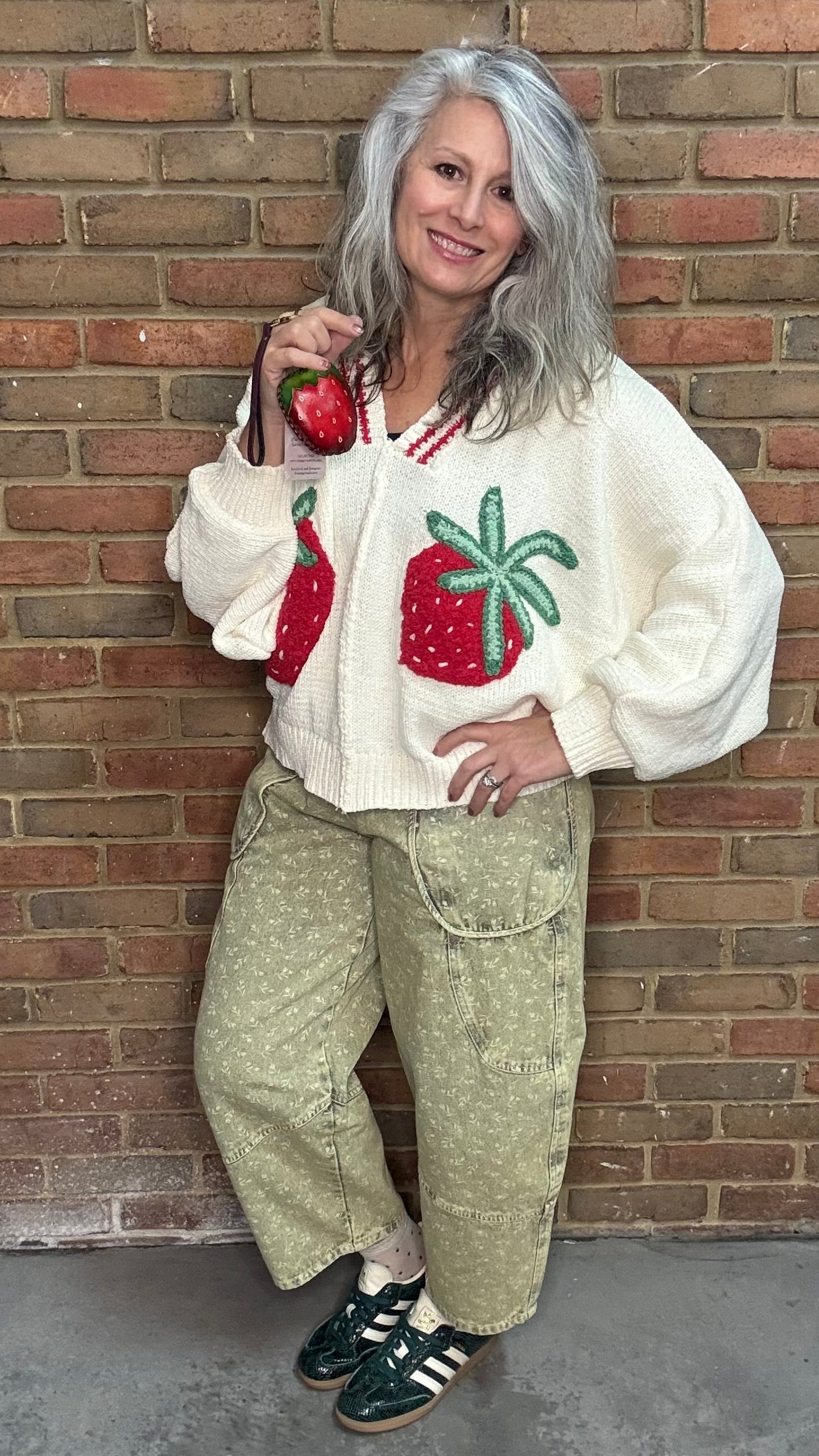 Person wearing the Strawberries on Cream Sweater and Floral Printed Barrel Pants standing against a brick wall.