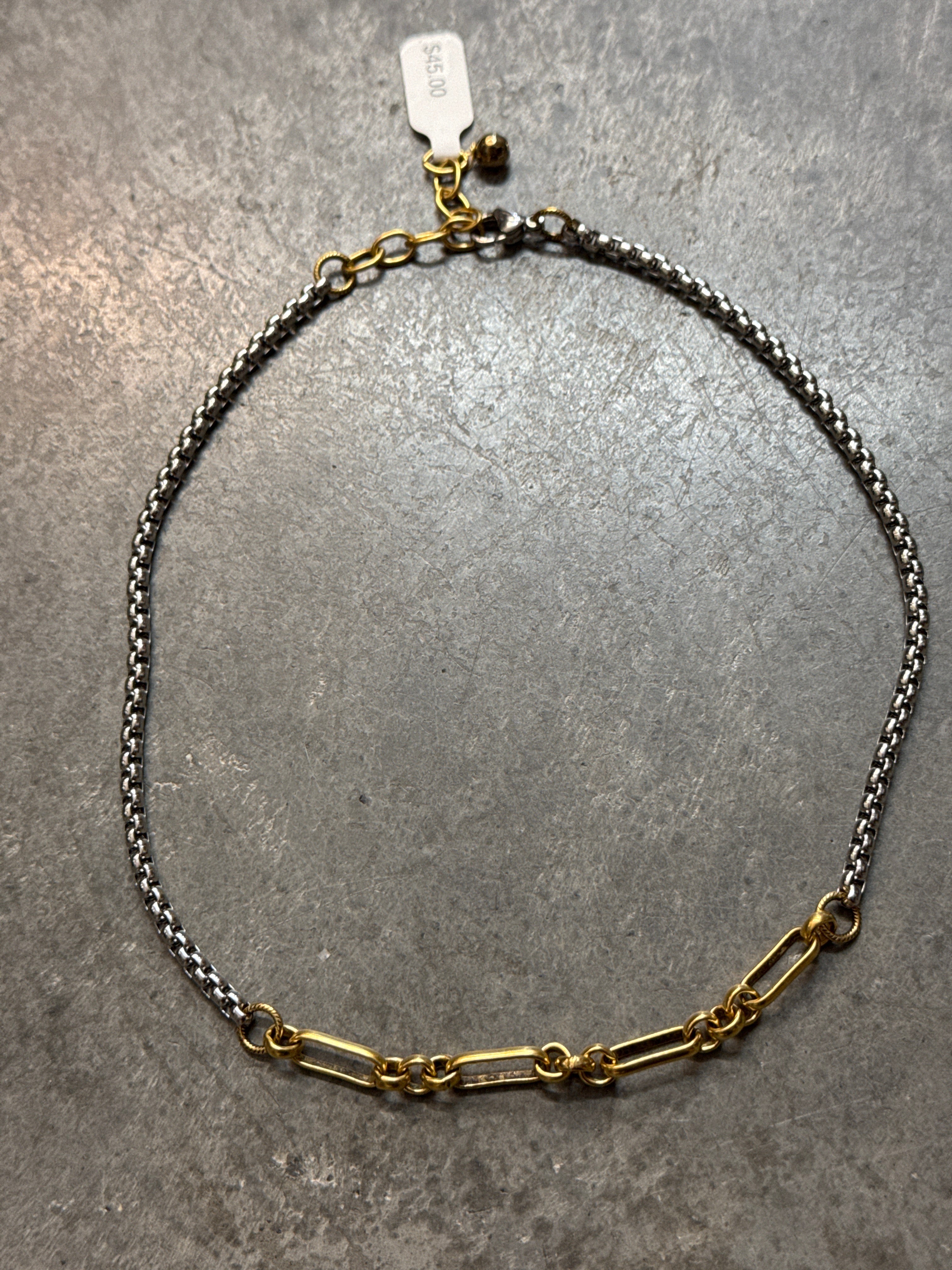 Gold and silver chain necklace on a gray surface