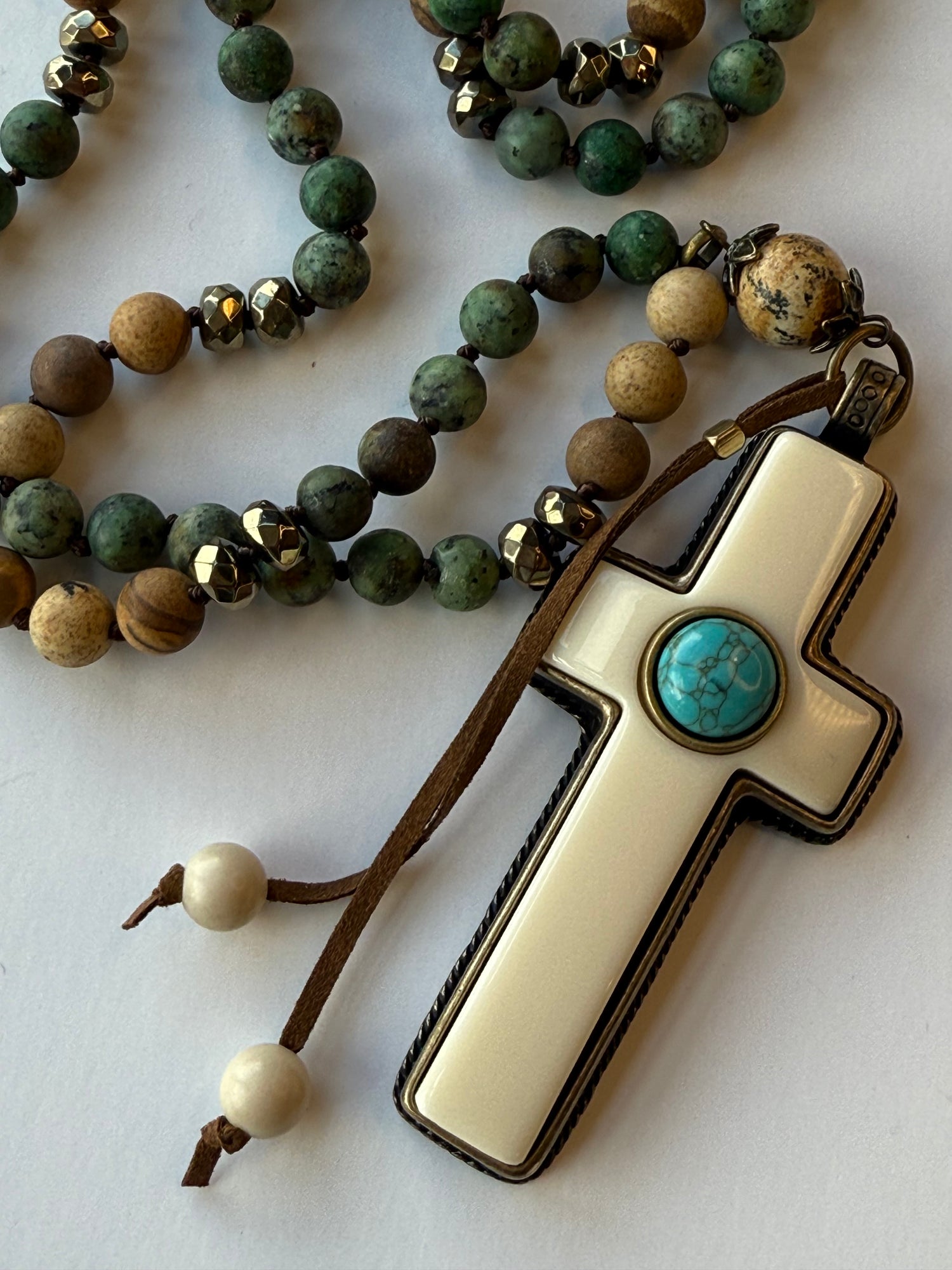 Necklace with green beads and a cross pendant on a white background