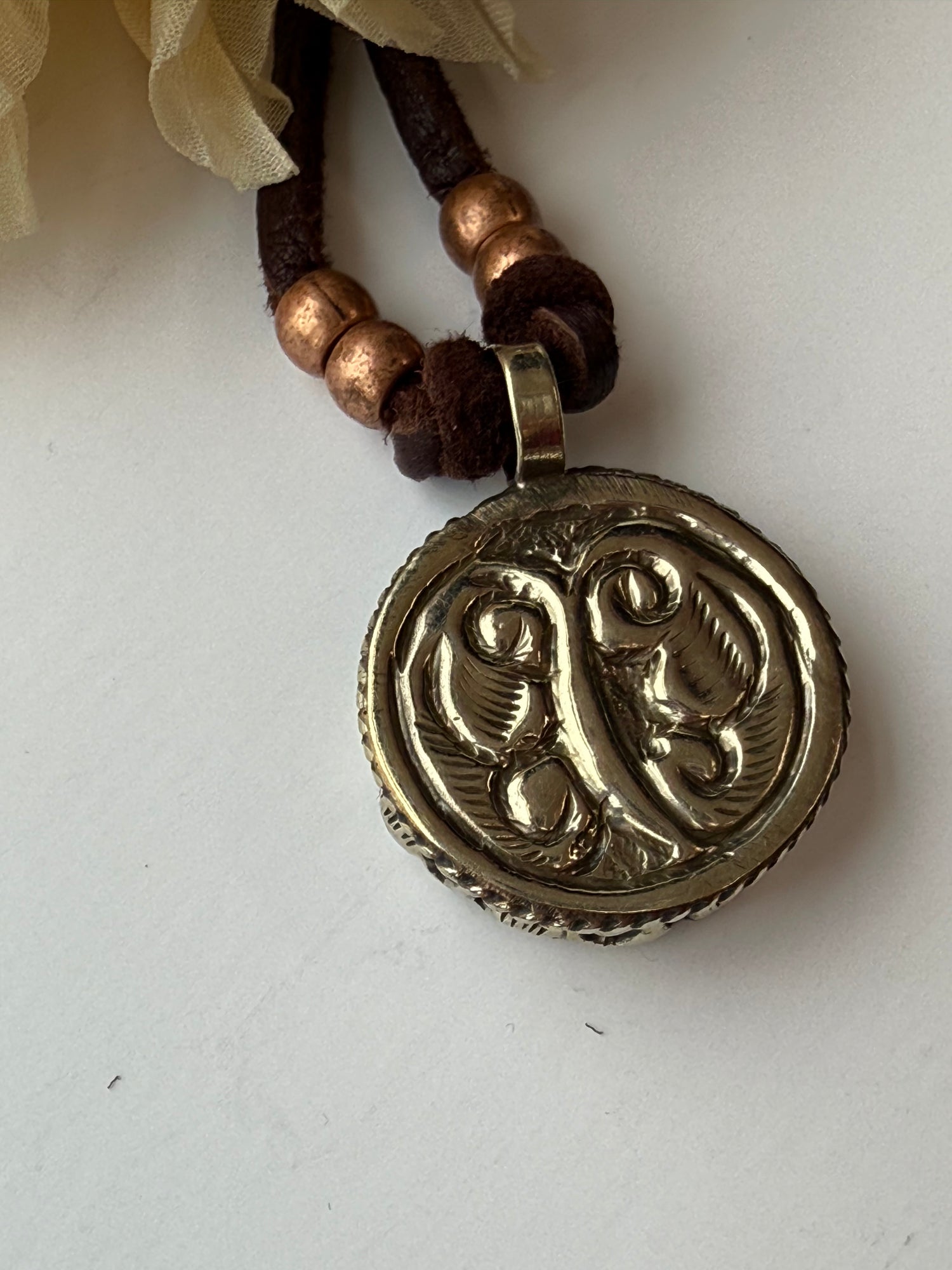 Back of sun pendant with intricate design on a white background