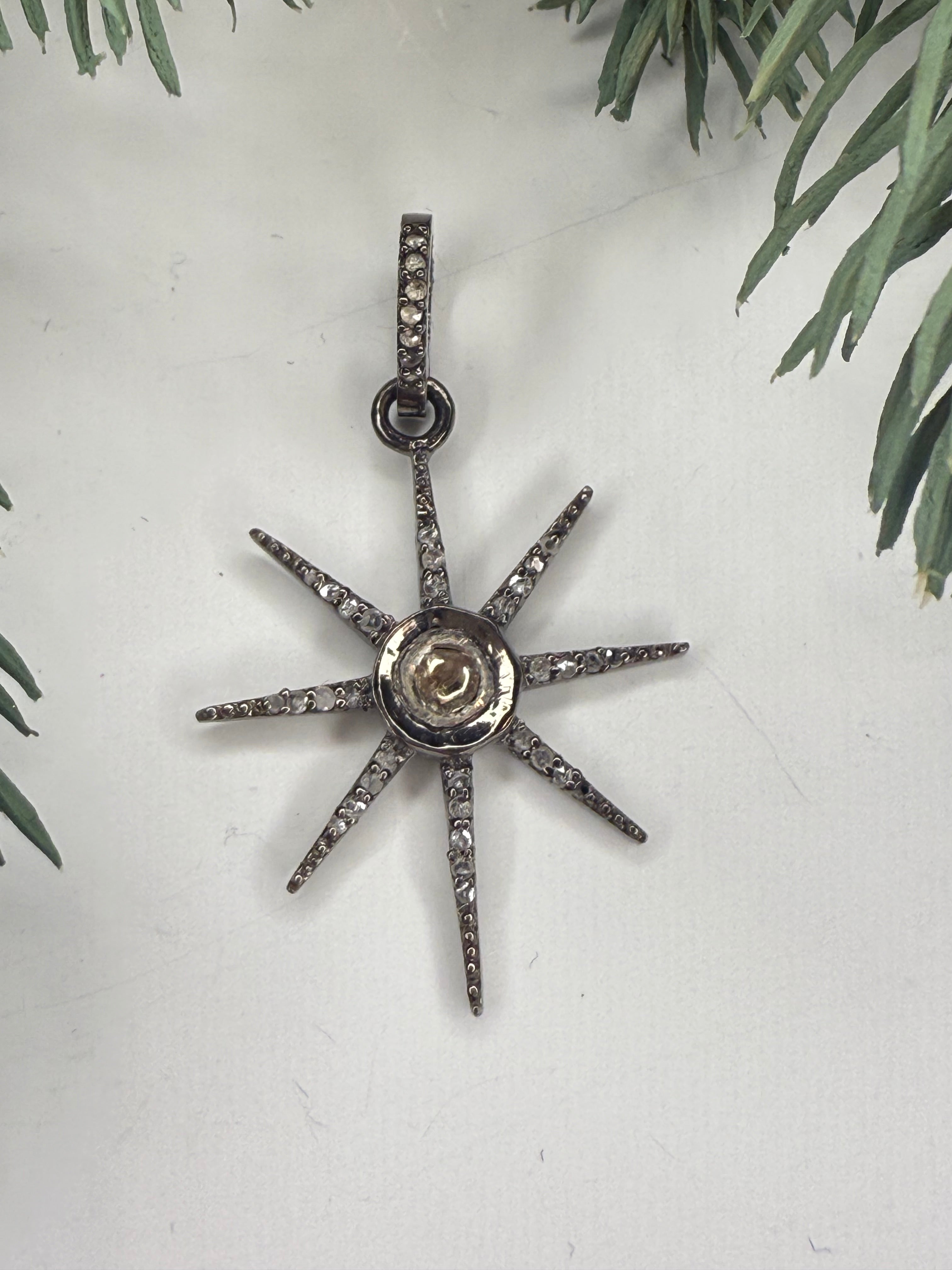 Star-shaped silver pendant with diamond stones on a light gray background