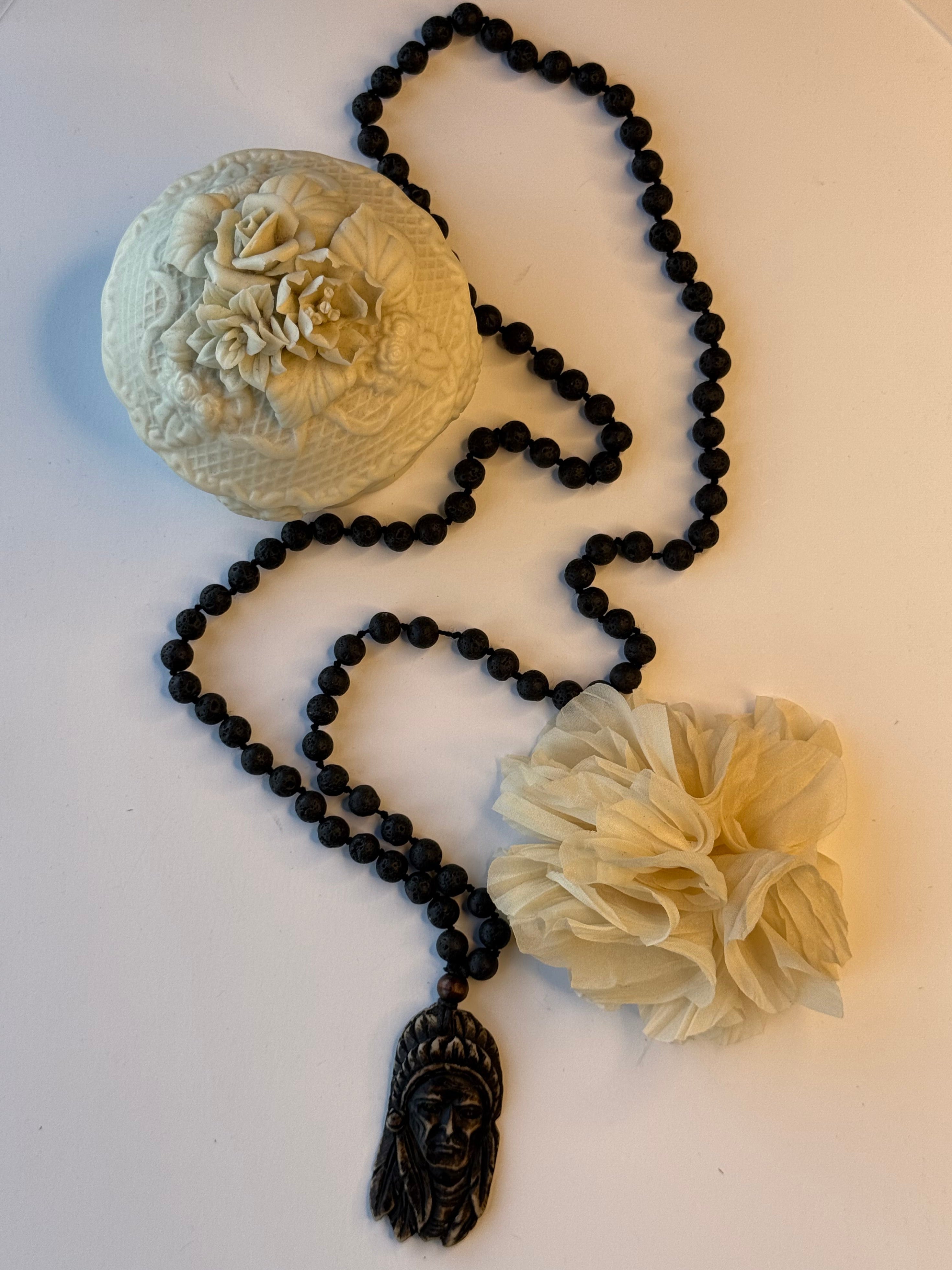 Black beaded necklace with Native American pendant on a white surface
