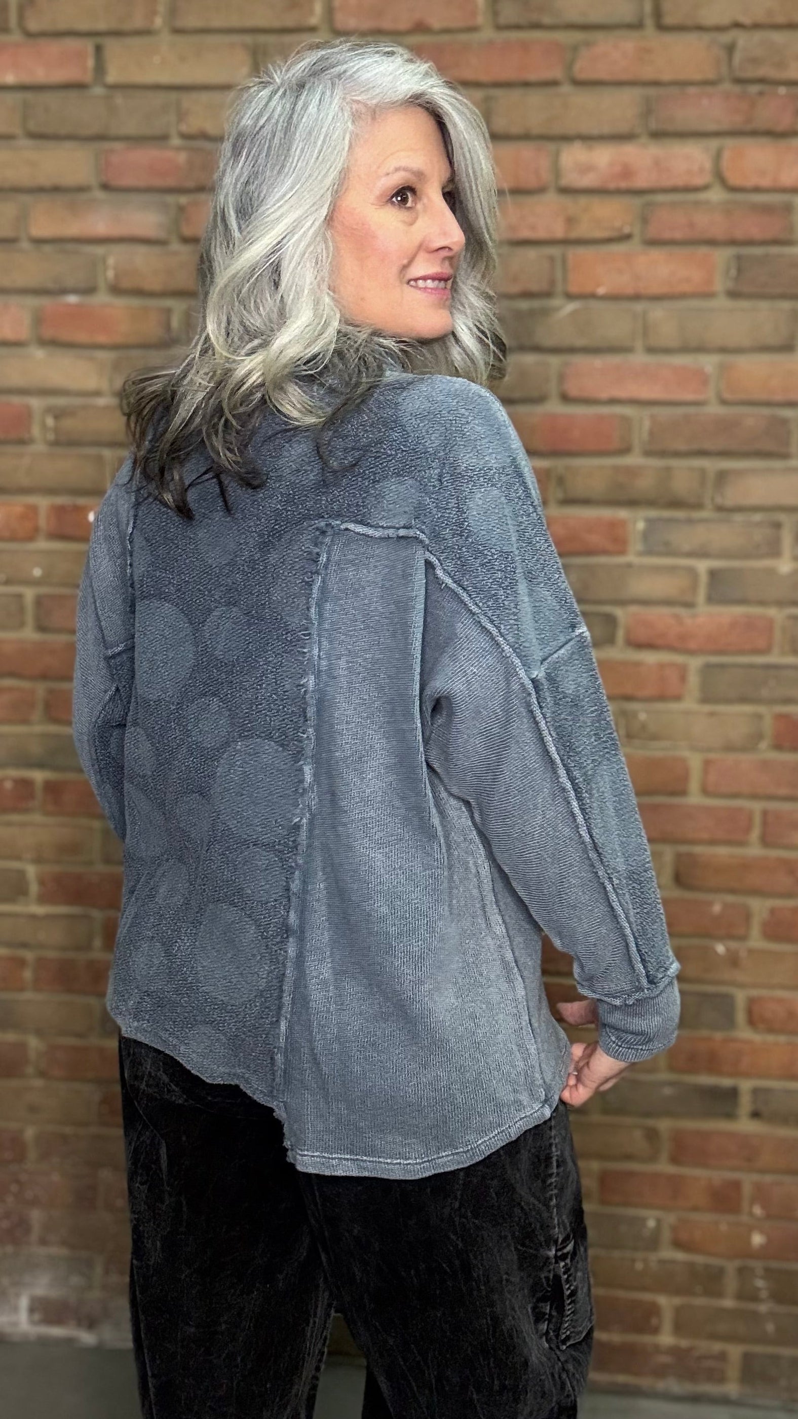 Person wearing the Adelia Top Chalice and the Karlene Corduroy Pants standing against a brick wall.