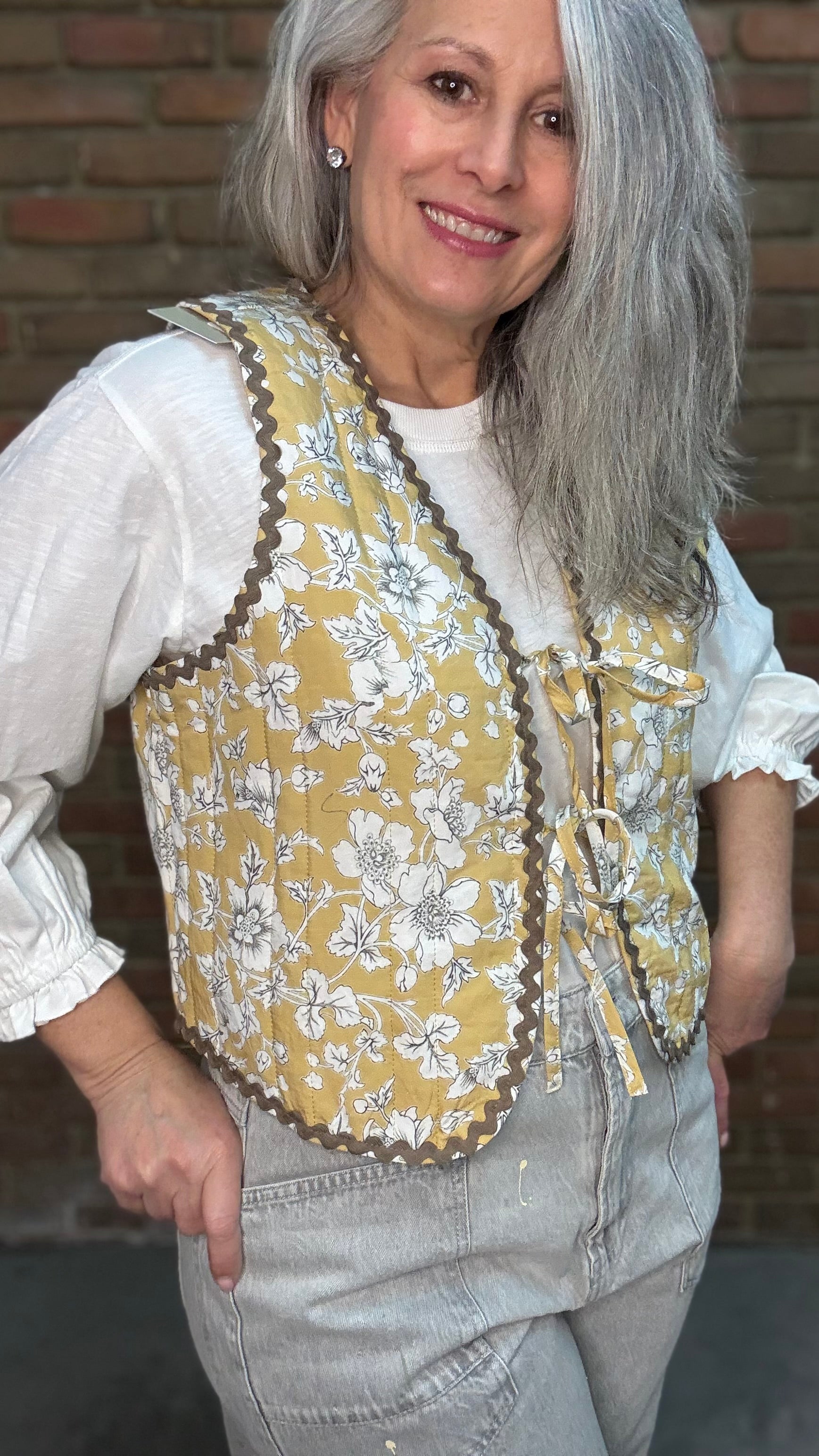 Woman wearing Quilted Tie Front Vest - Honey Bloom over Basic Long Sleeve Crew Neck Top paired with Oyster Grey Big Pocket Jeans.