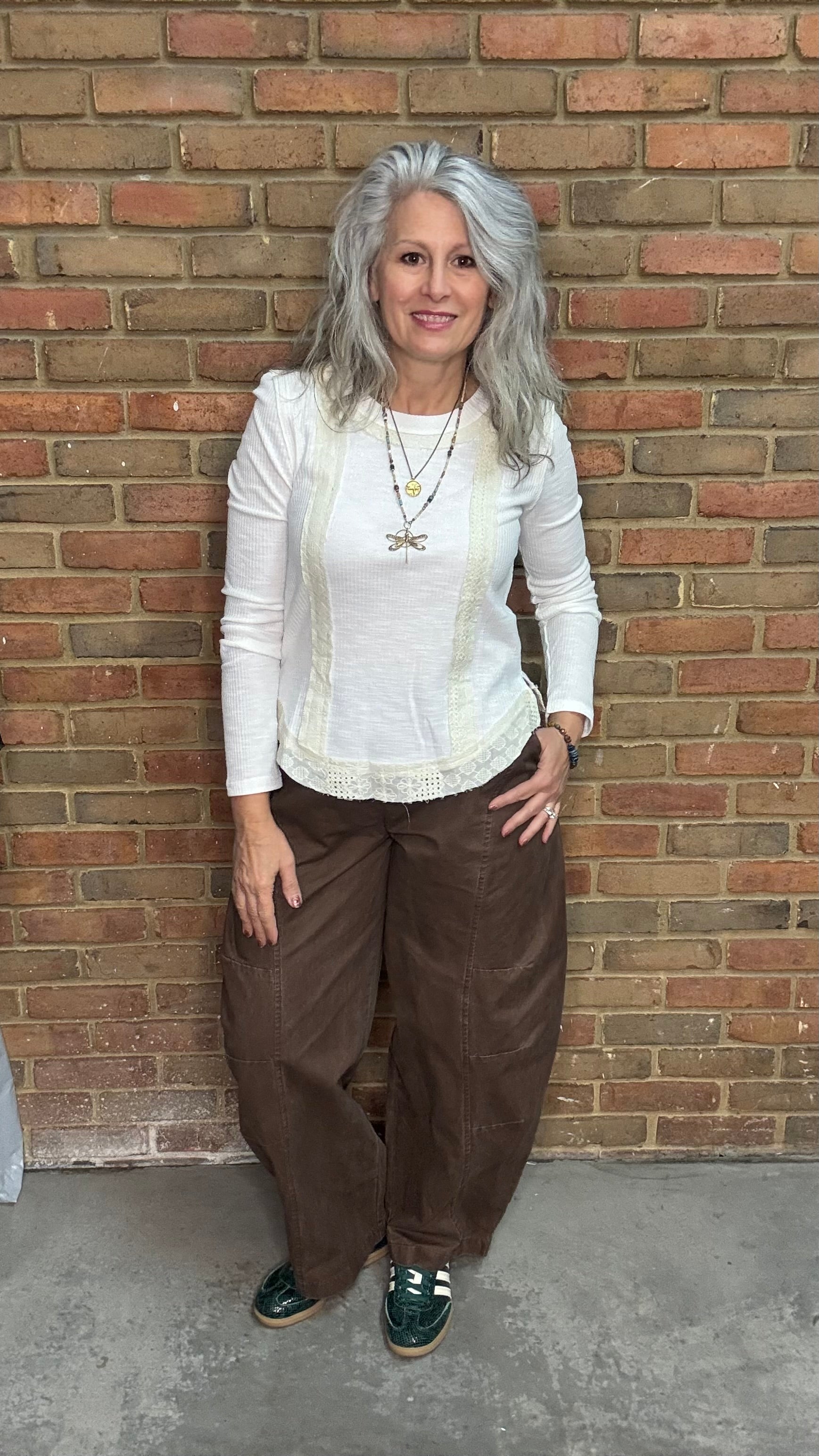 Woman standing against a brick wall wearing the Brown Pull On Barrel Pant.
