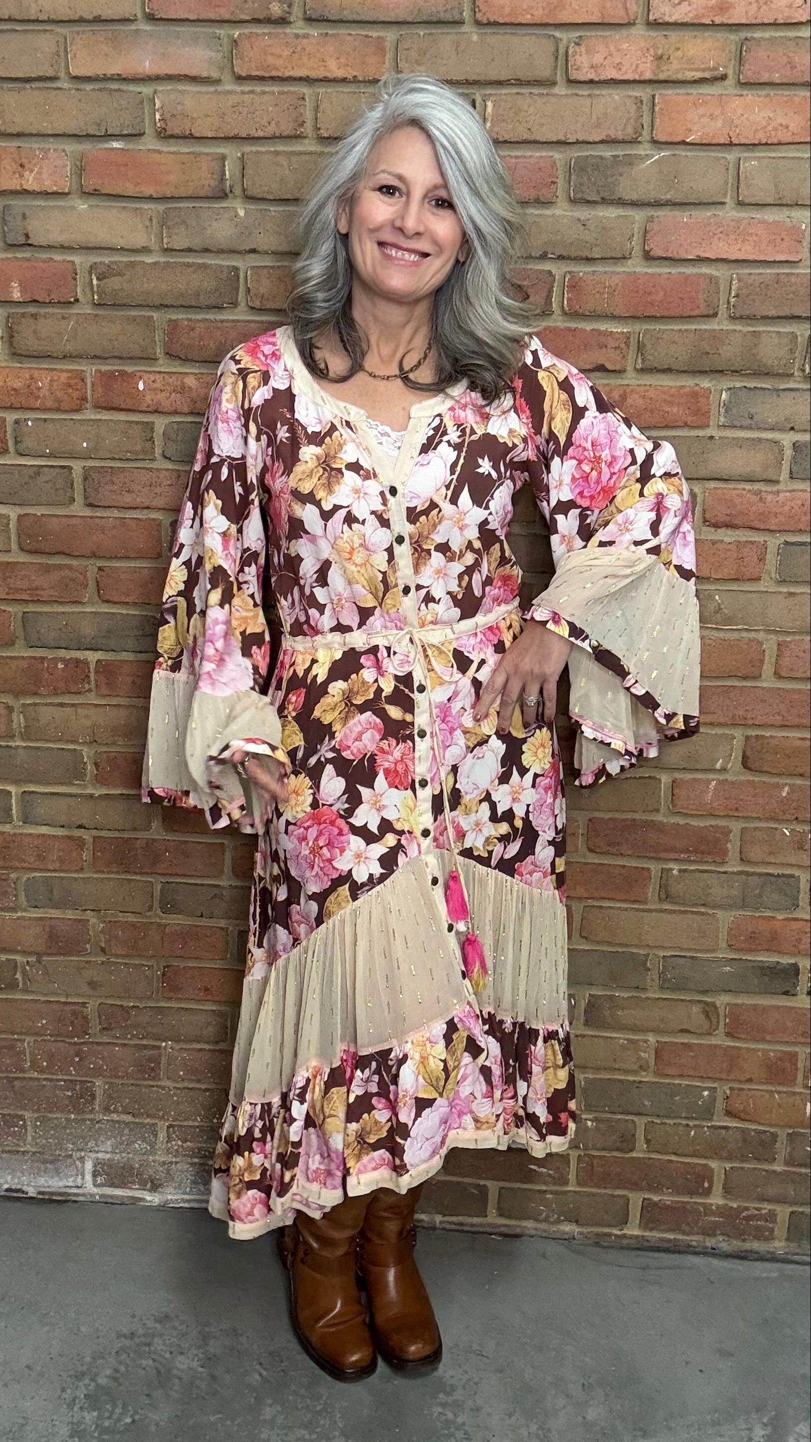 Woman wearing a floral dress standing against a brick wall