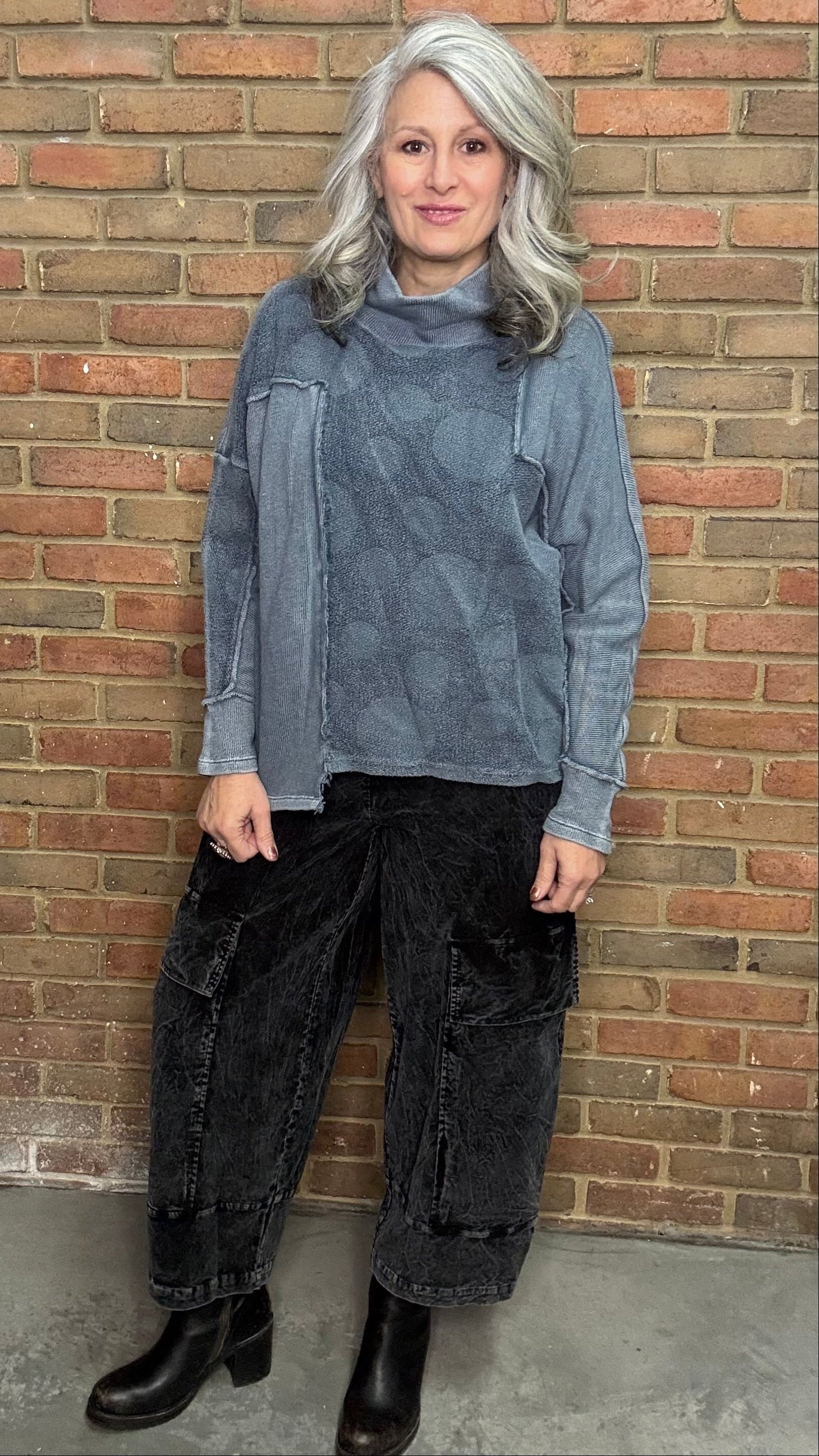 Person wearing the Adelia Top Chalice and the Karlene Corduroy Pants standing against a brick wall.