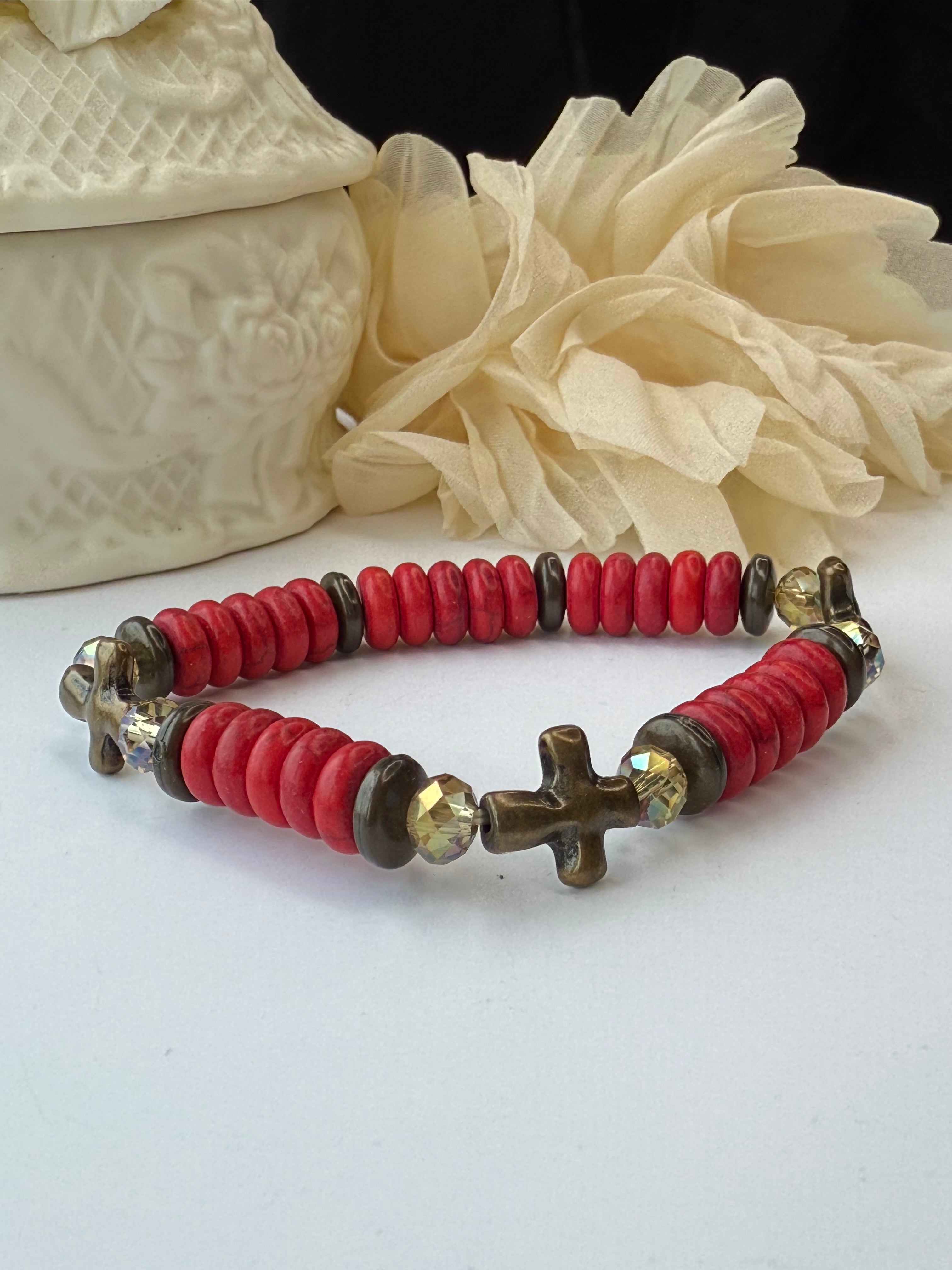 Bracelet with red beads and a cross charm on a white background