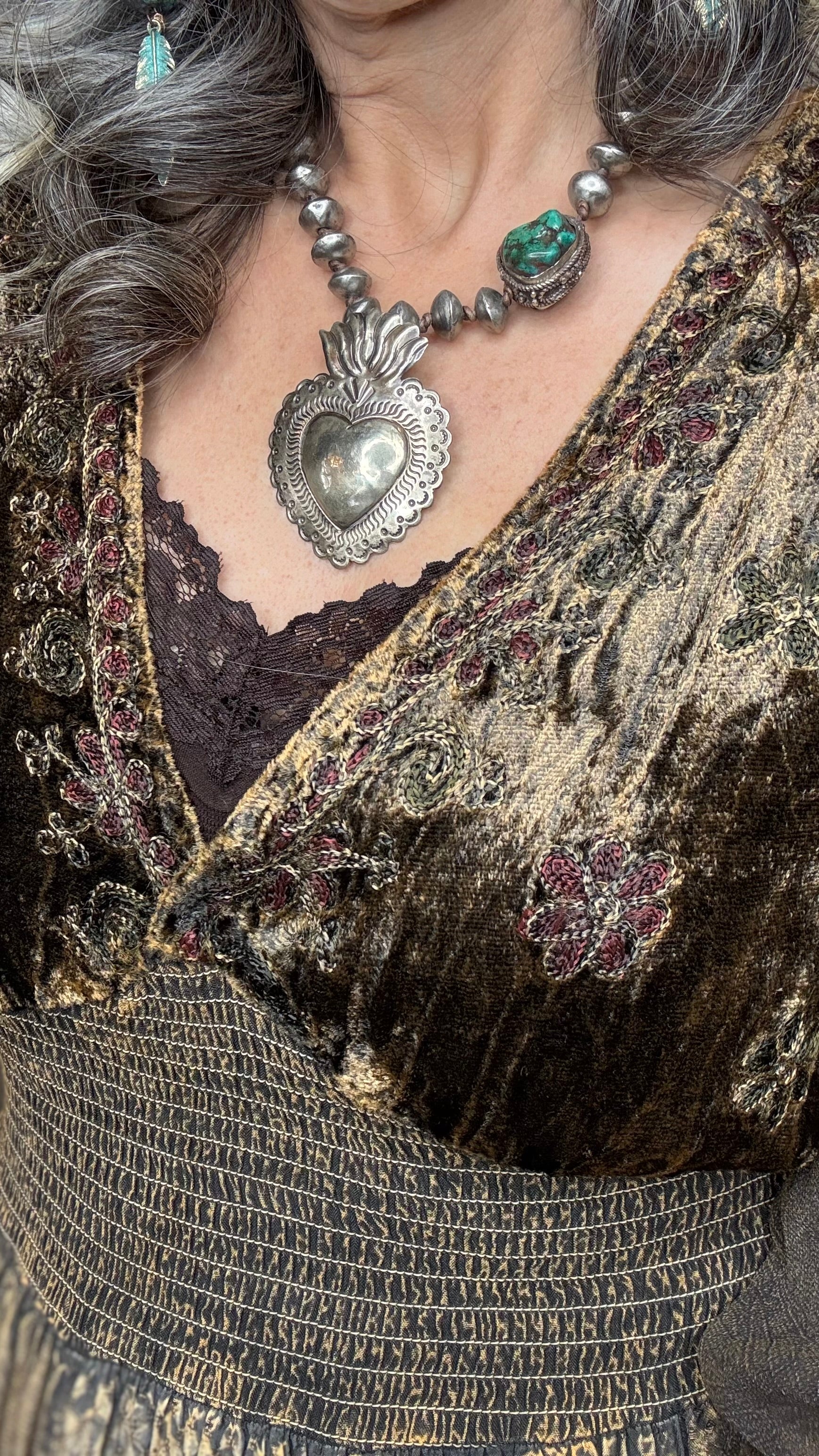 Close-up of a Woman in Amber Smocked Patchwork Babydoll dress wearing the Sacred Heart Turquoise Necklace.