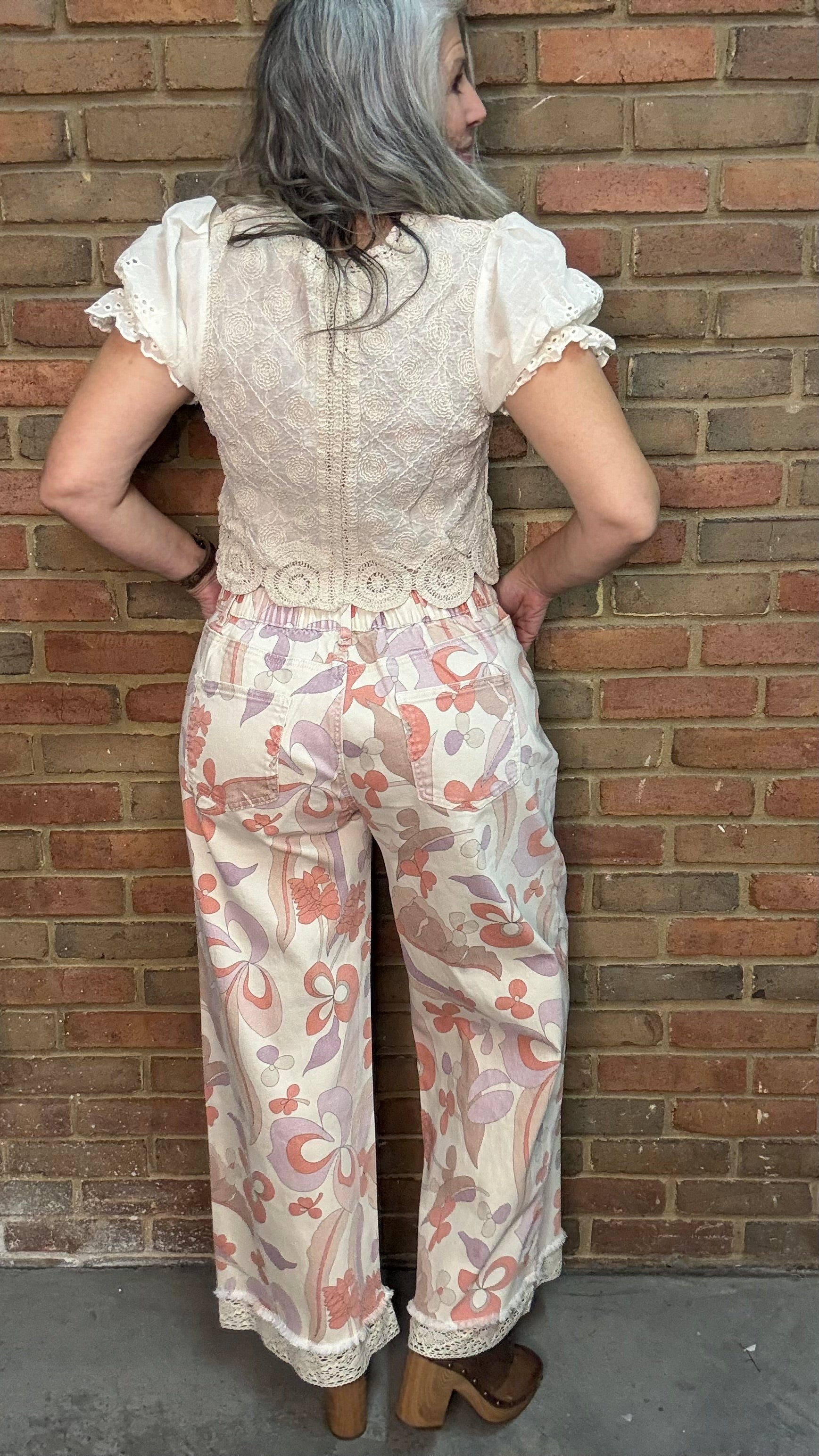 Woman wearing the Groovy Print Denim Pants standing against a brick wall.