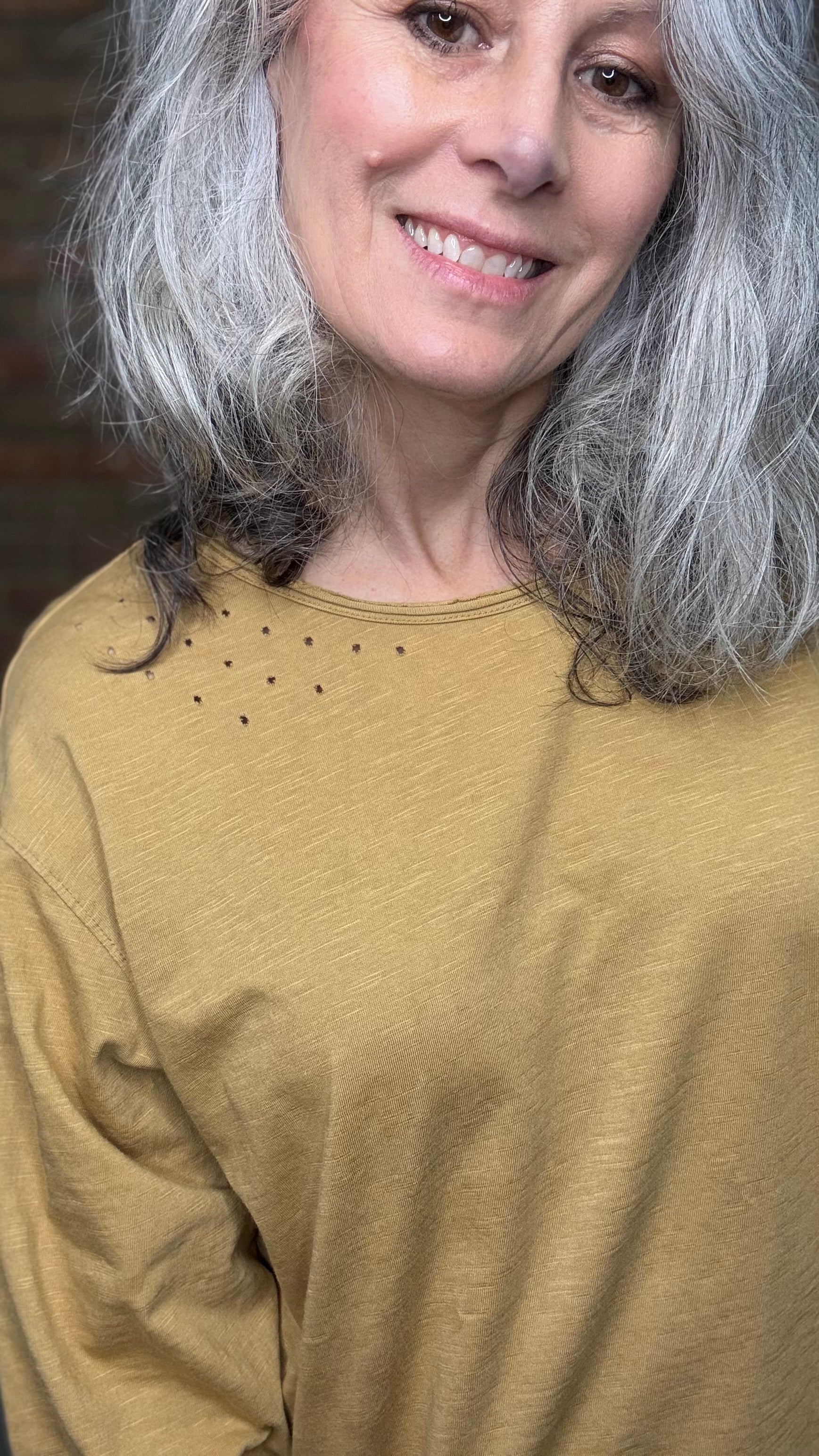 Woman with gray hair wearing a mustard yellow sweater