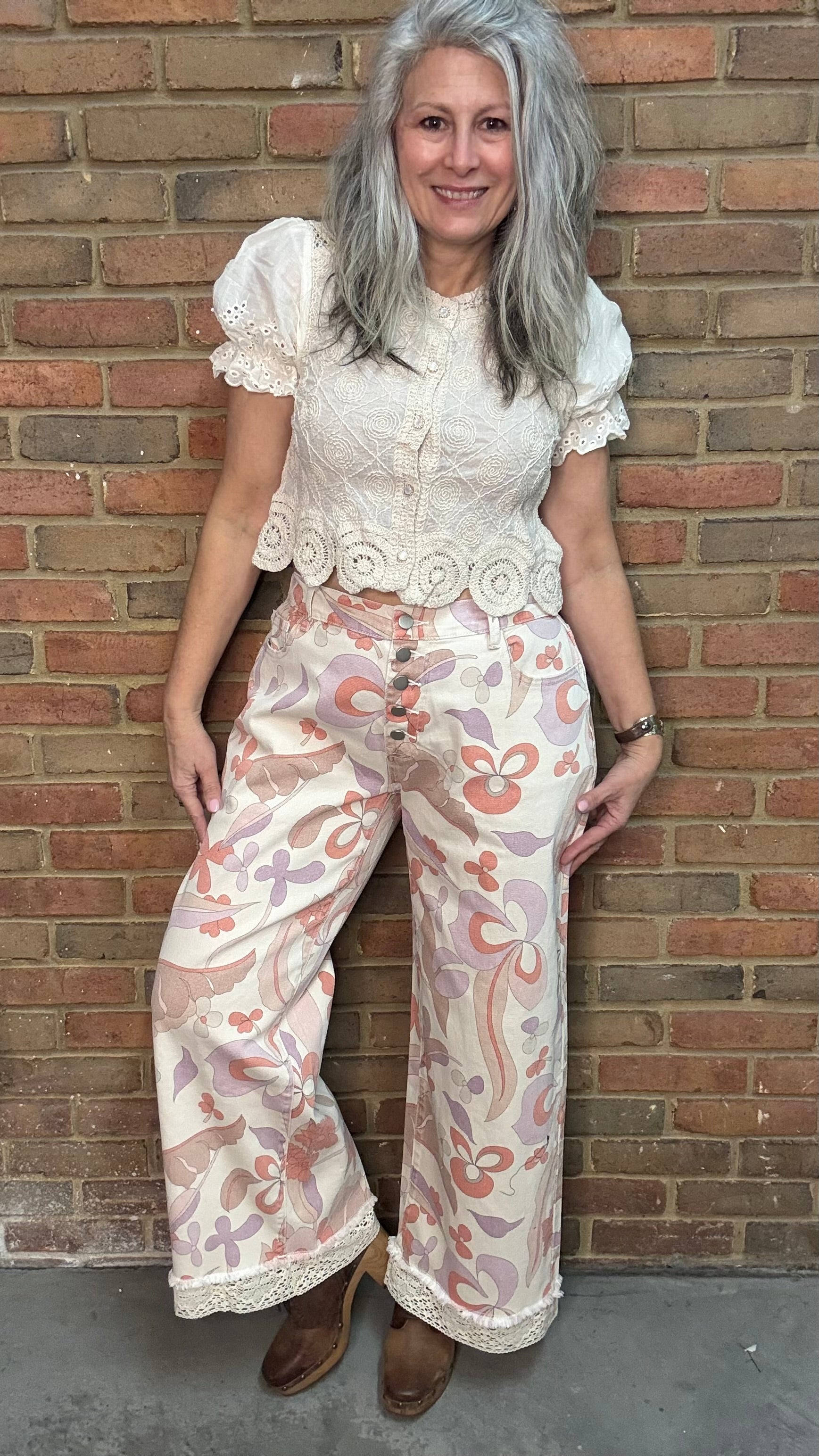 Woman wearing the Groovy Print Denim Pants standing against a brick wall.