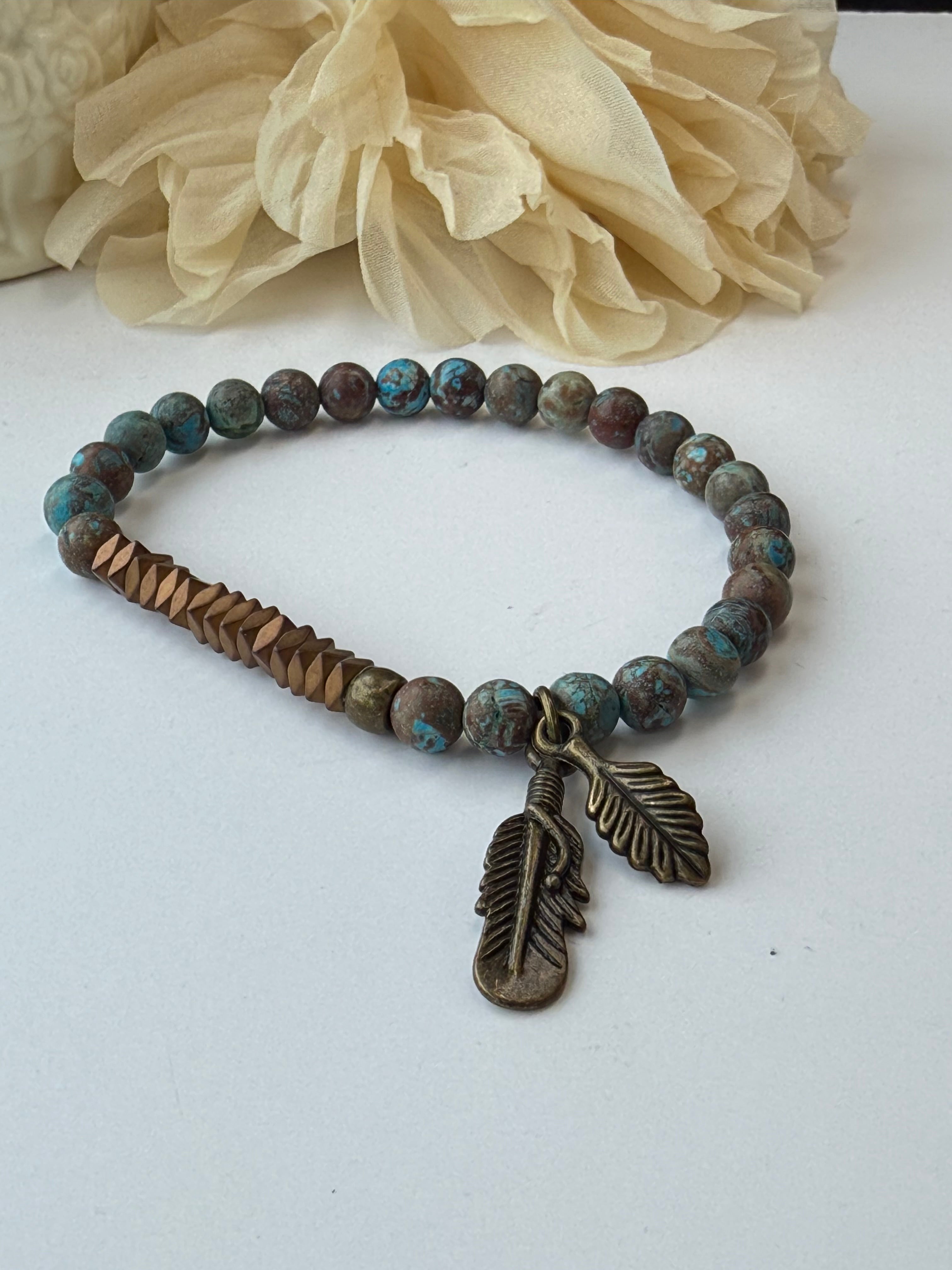 Bracelet with bead design and feather charm on a white background