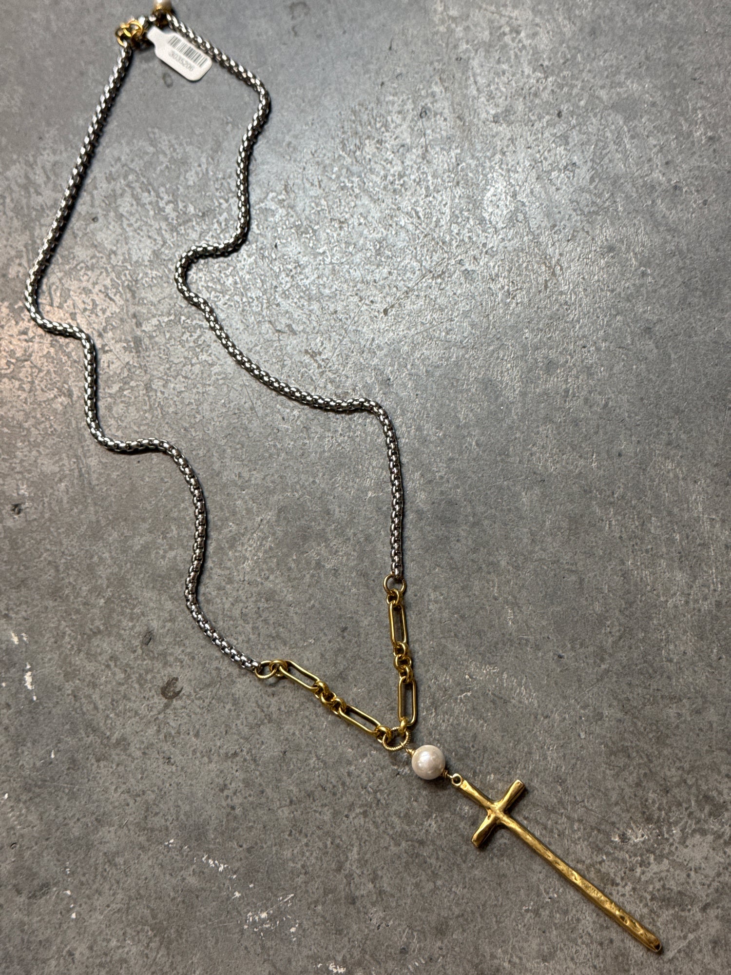 Necklace with a cross pendant and pearl on a gray surface