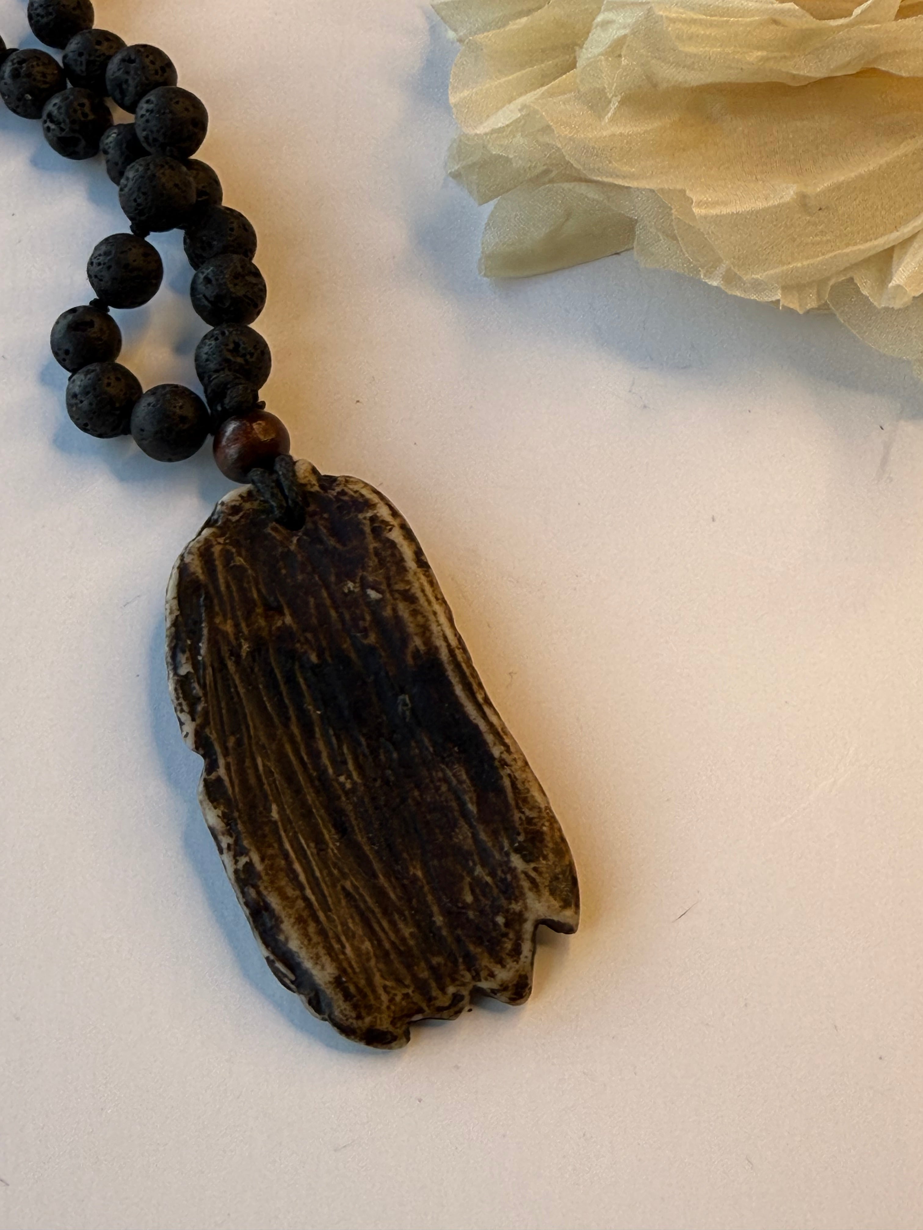 Black beaded necklace with back of pendant on a light background