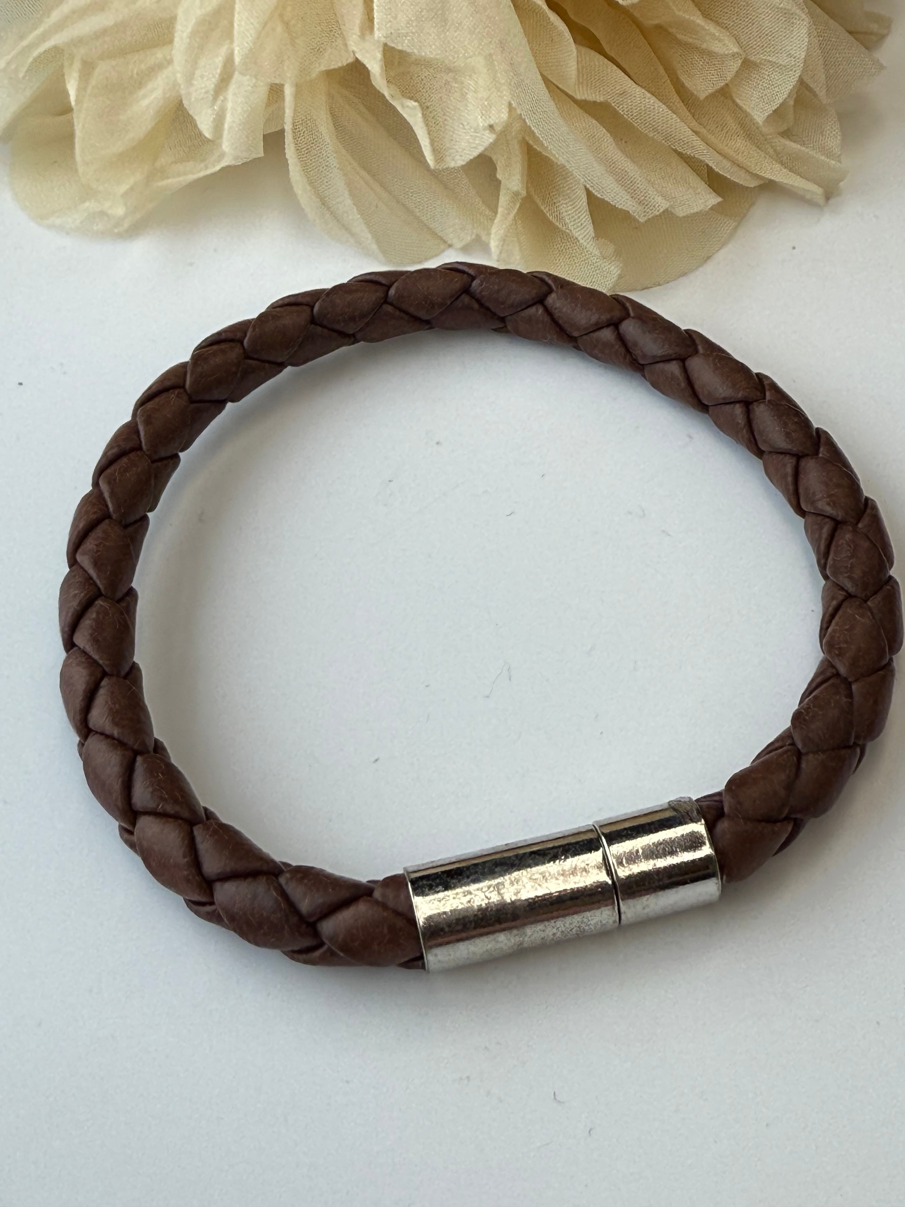 Brown braided leather bracelet with a silver clasp on a white background