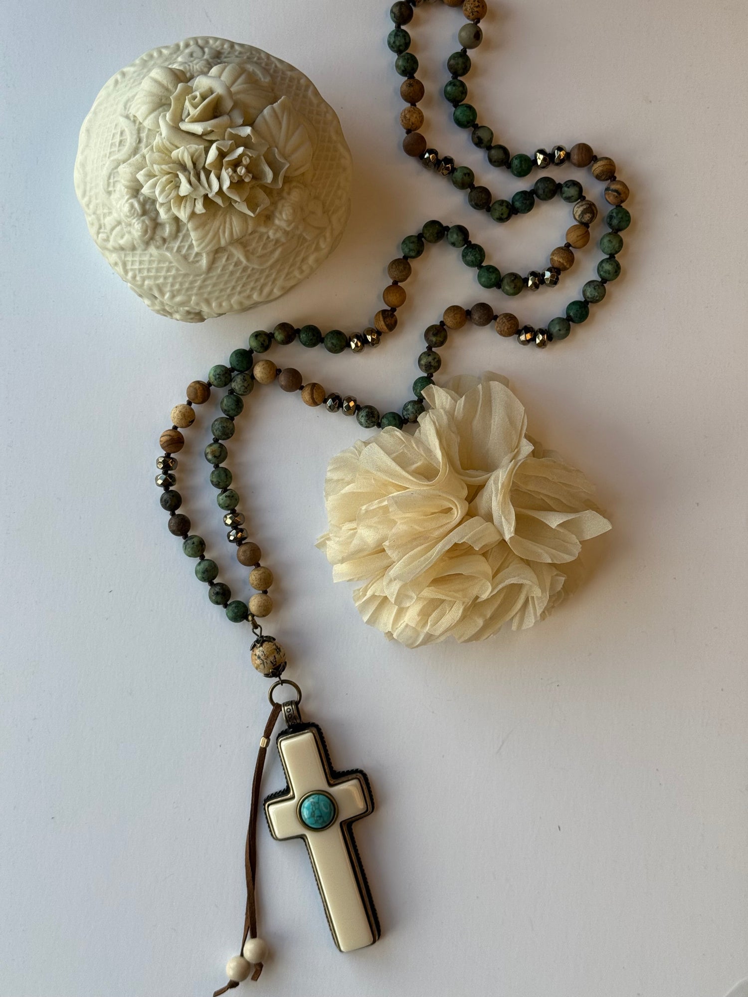 Necklace with beads, decorative pendants, and a cross on a white surface