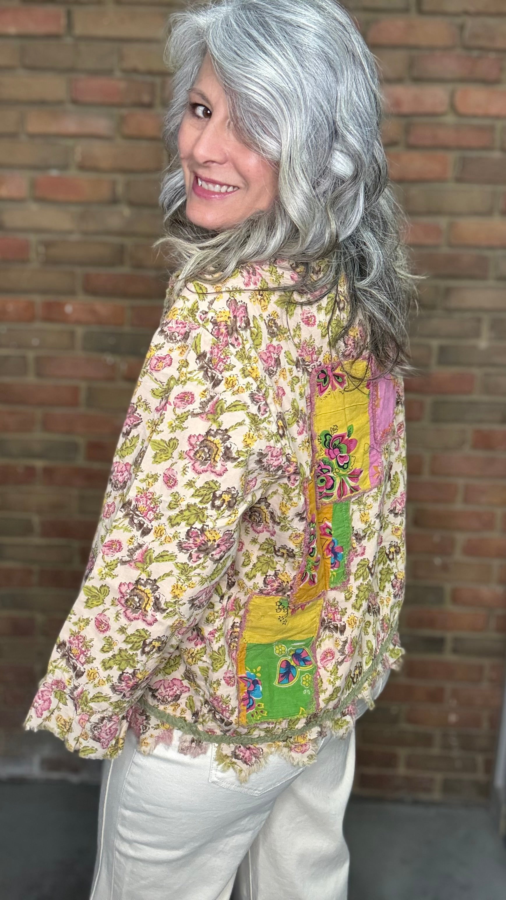 Woman wearing Desert Winds Top against a brick wall.