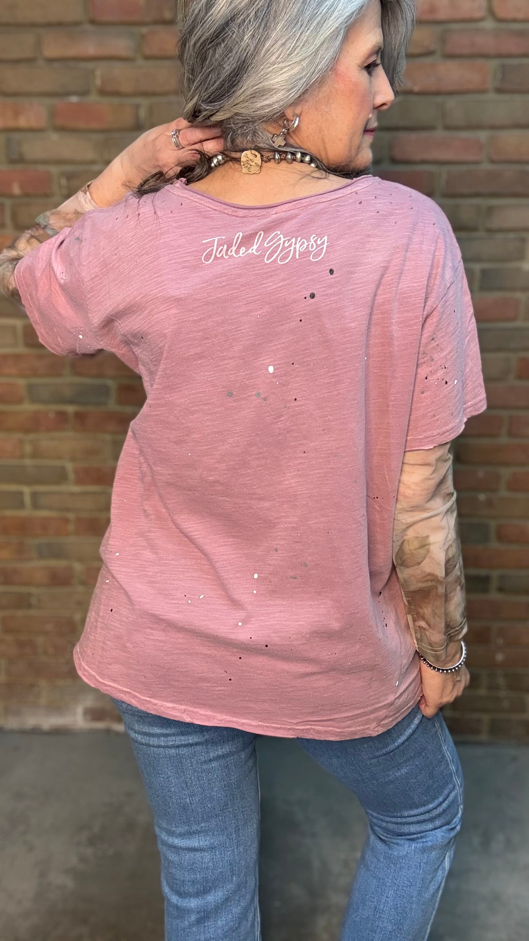 Woman wearing Moon Dance Tee - Cherished Heart tee against brick wall.