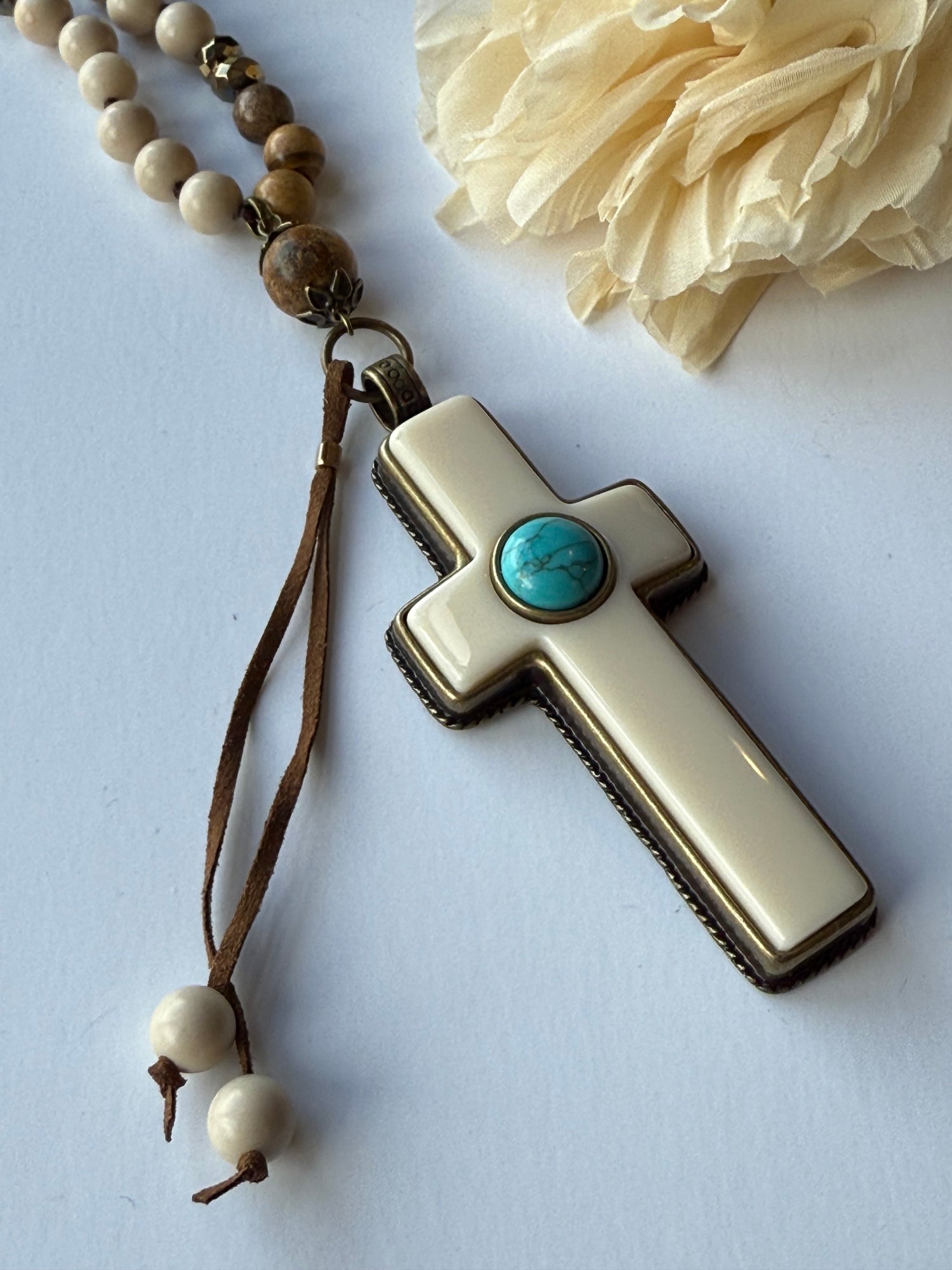 Bone cross pendent with turquoise stone on a white background