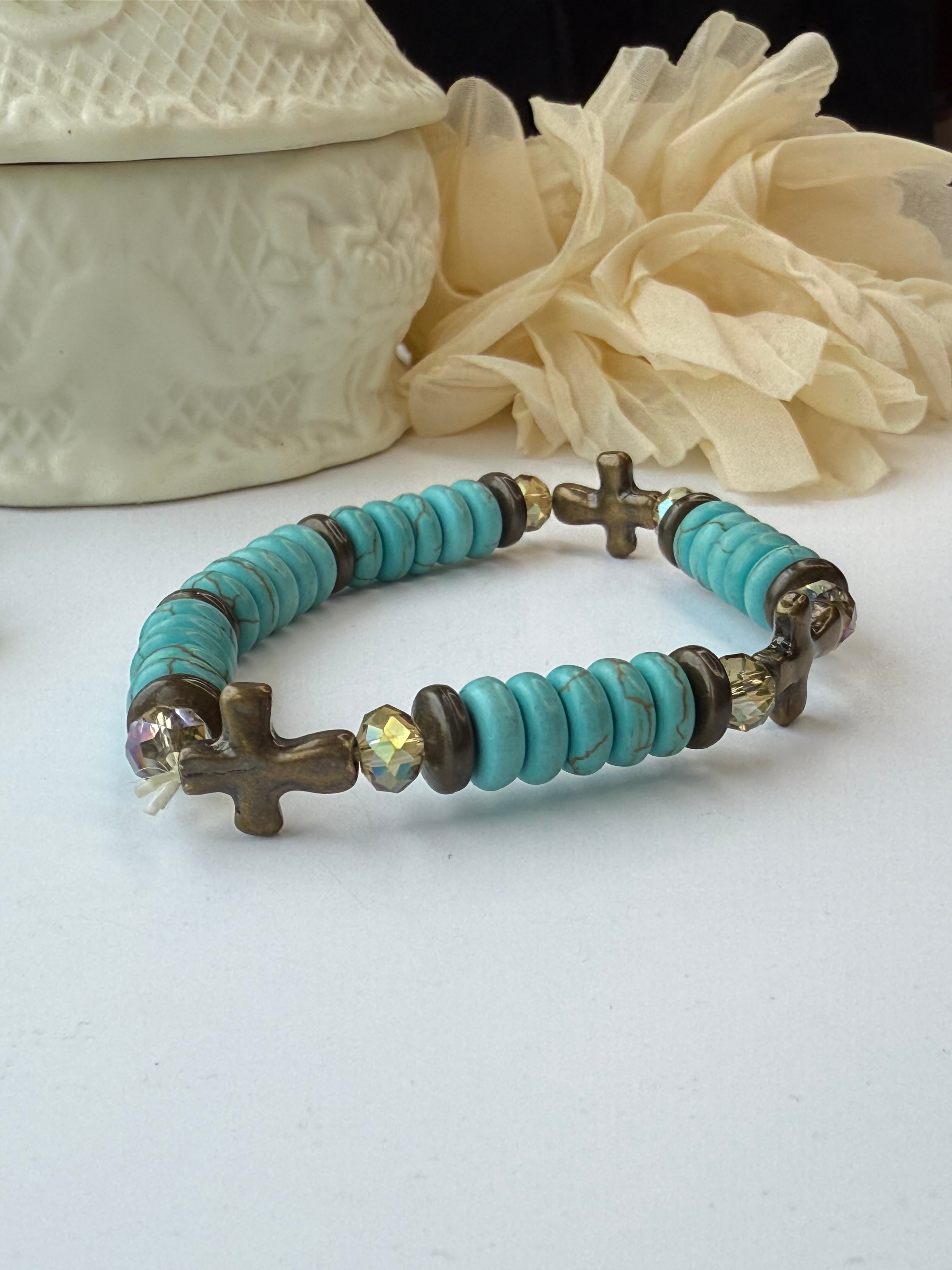 Turquoise beaded bracelet with metal cross accents on a white background