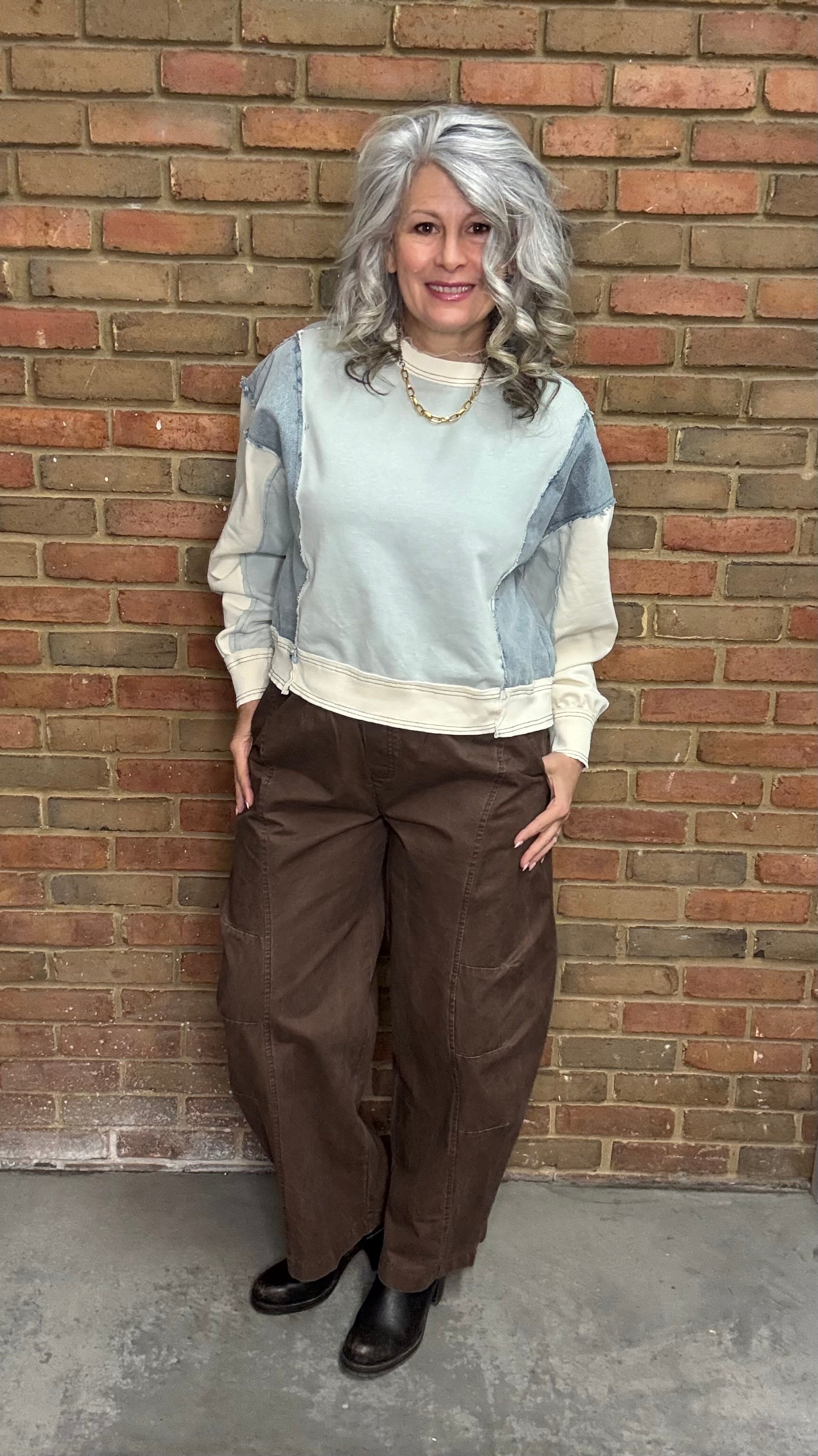 Person wearing the blue Color Block Pull on with the Brown Pull On Barrel Pants, standing against a brick wall.