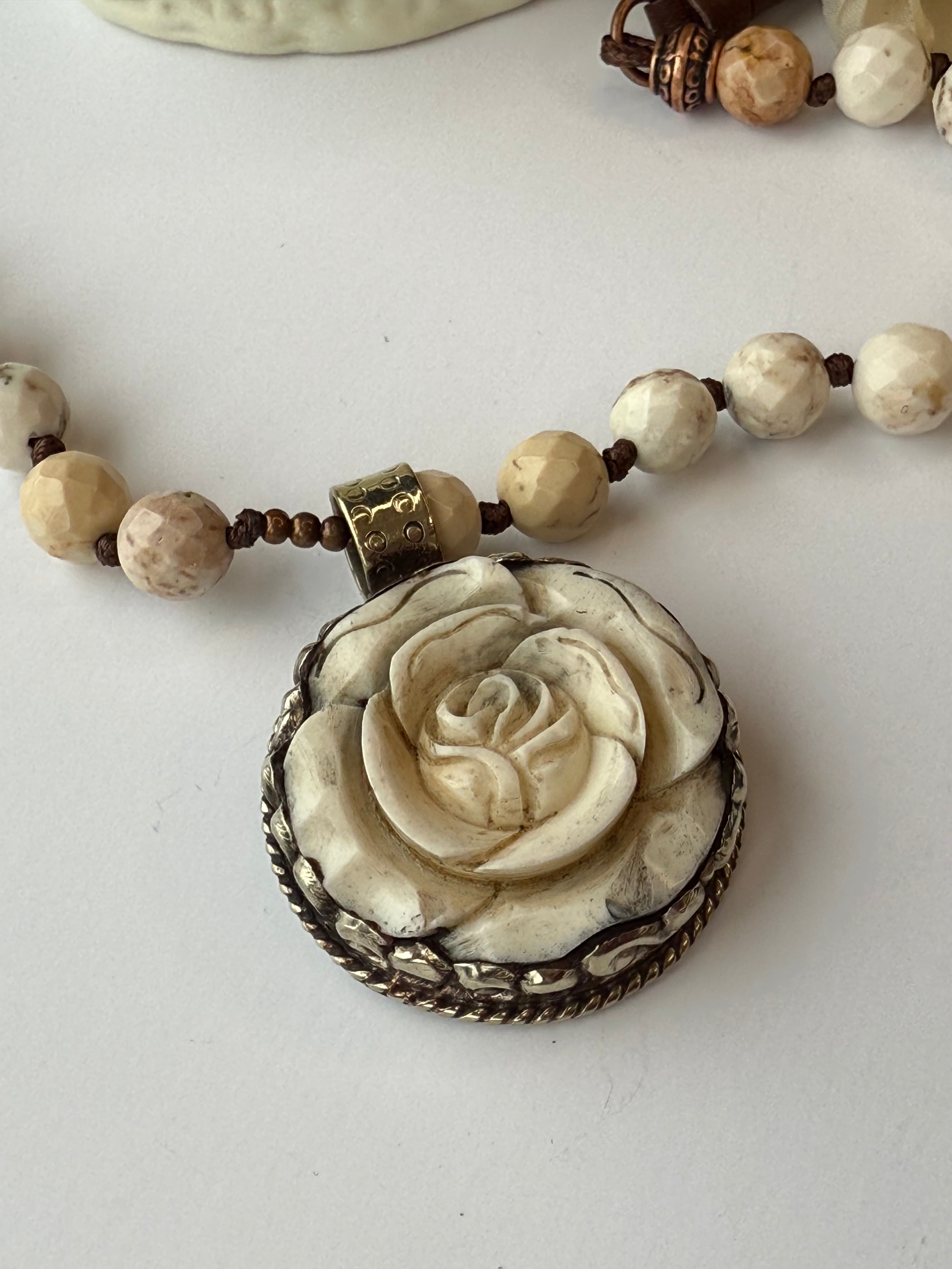 Necklace with a large rose pendant and beaded chain on a white background