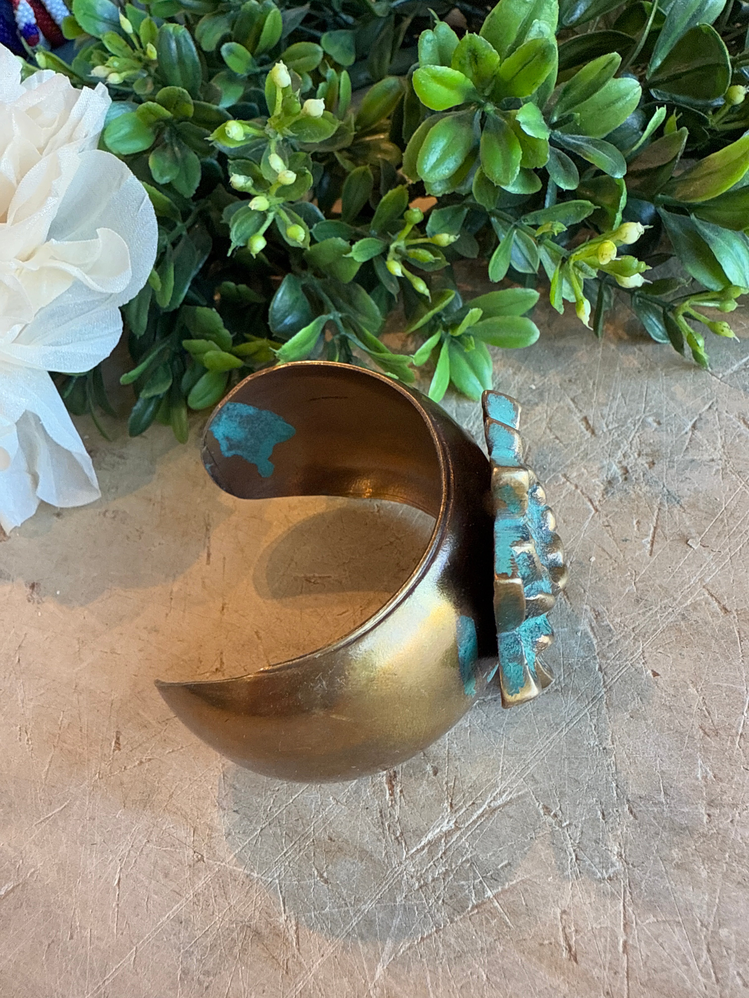 Brass Lotus Cuff on a textured surface with greenery