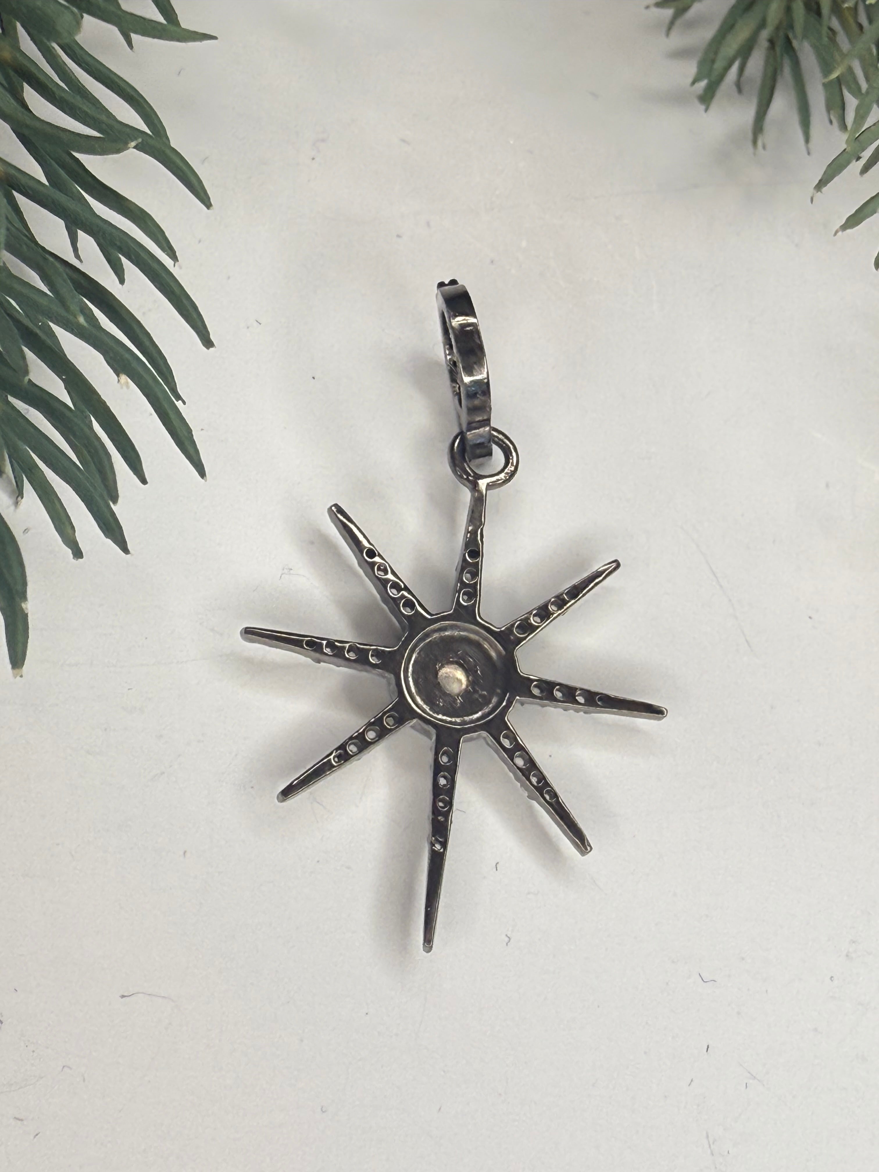 Back of star-shaped pendant on a light background with greenery.