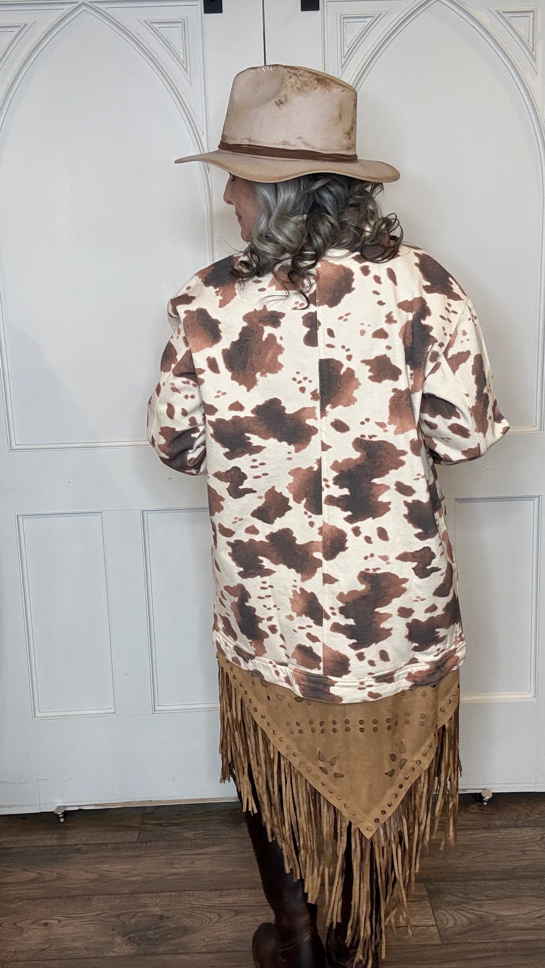 Woman wearing the Cow Print Denim Jacket, the Camel Faux Suede Fringe Skirt, topped the solid Mesh top in Brown and the Wide Triangle Buckle Belt. Shoes are the Lane Plain Jane Boots, and she is wearing the Pop&