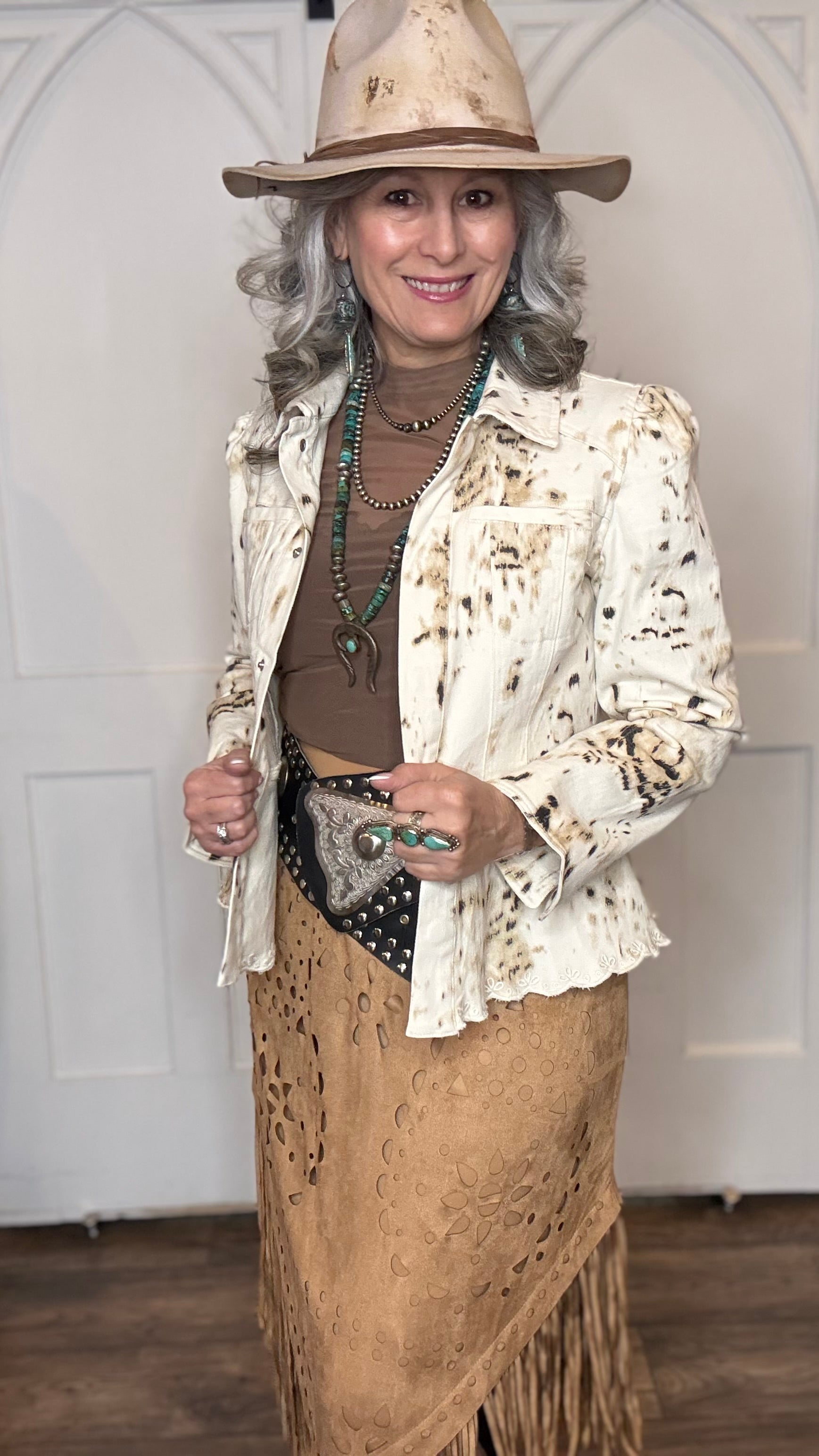 Woman wearing the Cow Print Scallop Edge Jacket with the Camel Faux Suede Fringe Skirt with the Pop&