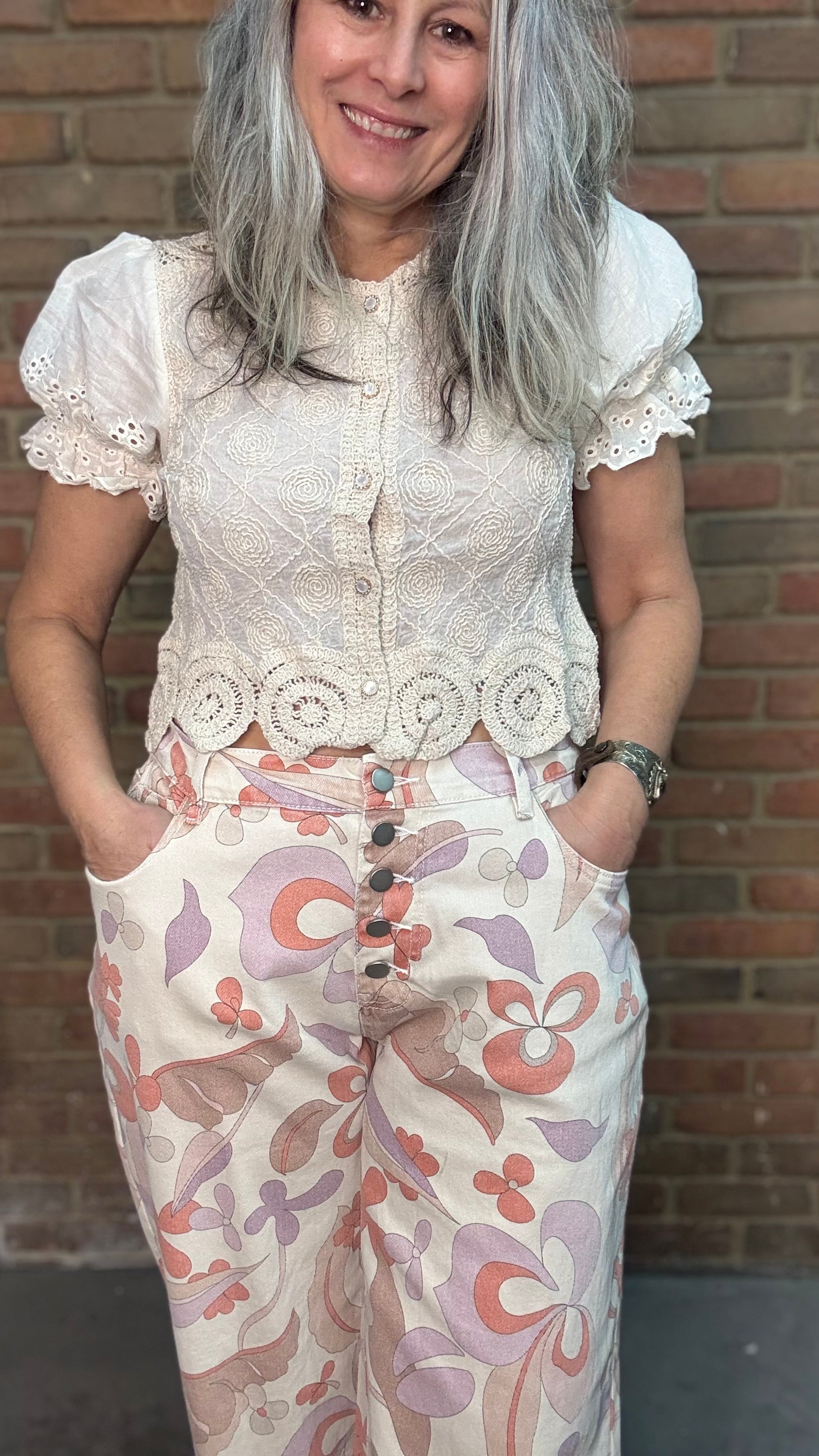 Woman wearing the Groovy Print Denim Pants standing against a brick wall.