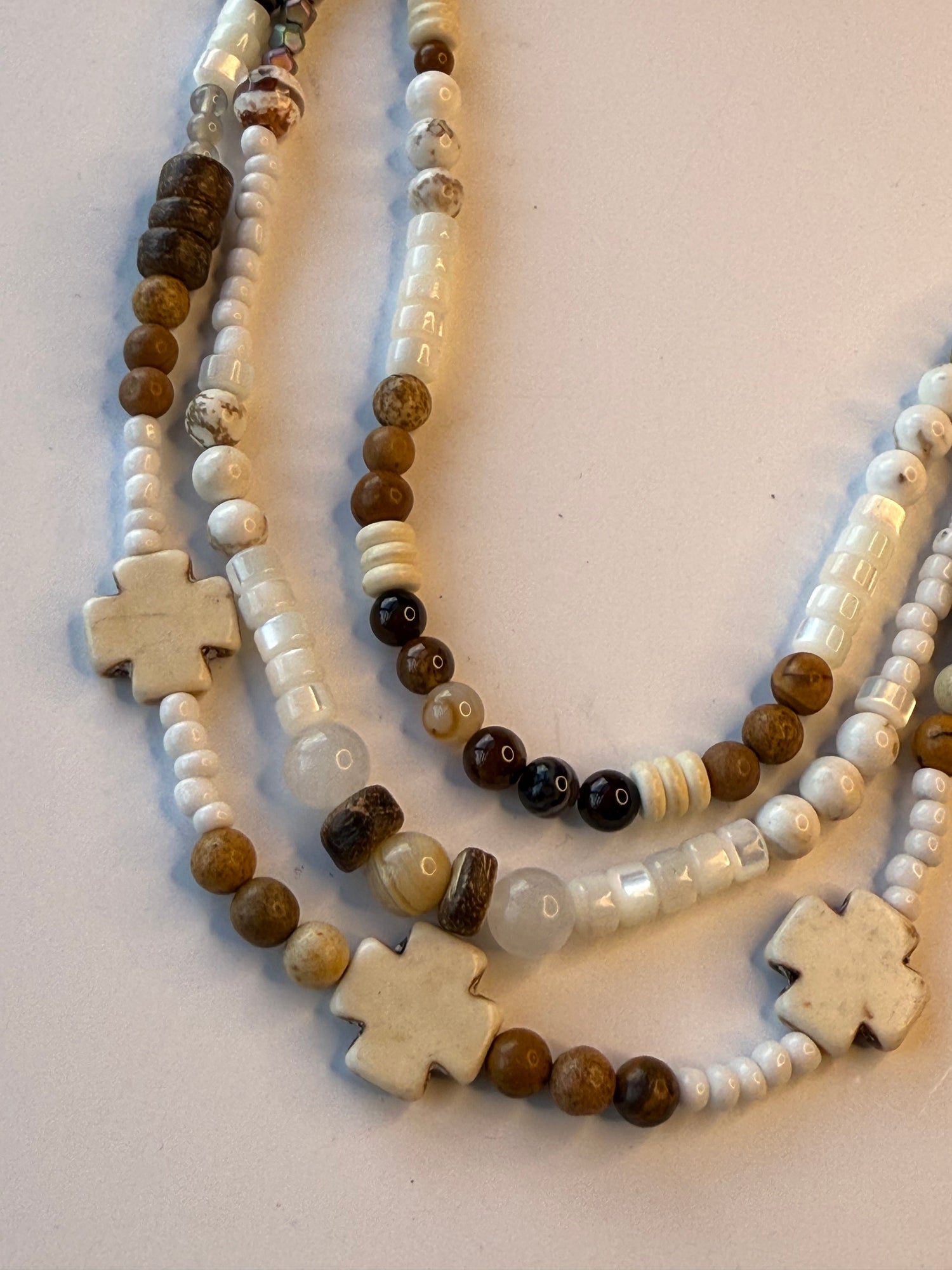 Beaded necklace with cross-shaped beads on a light background