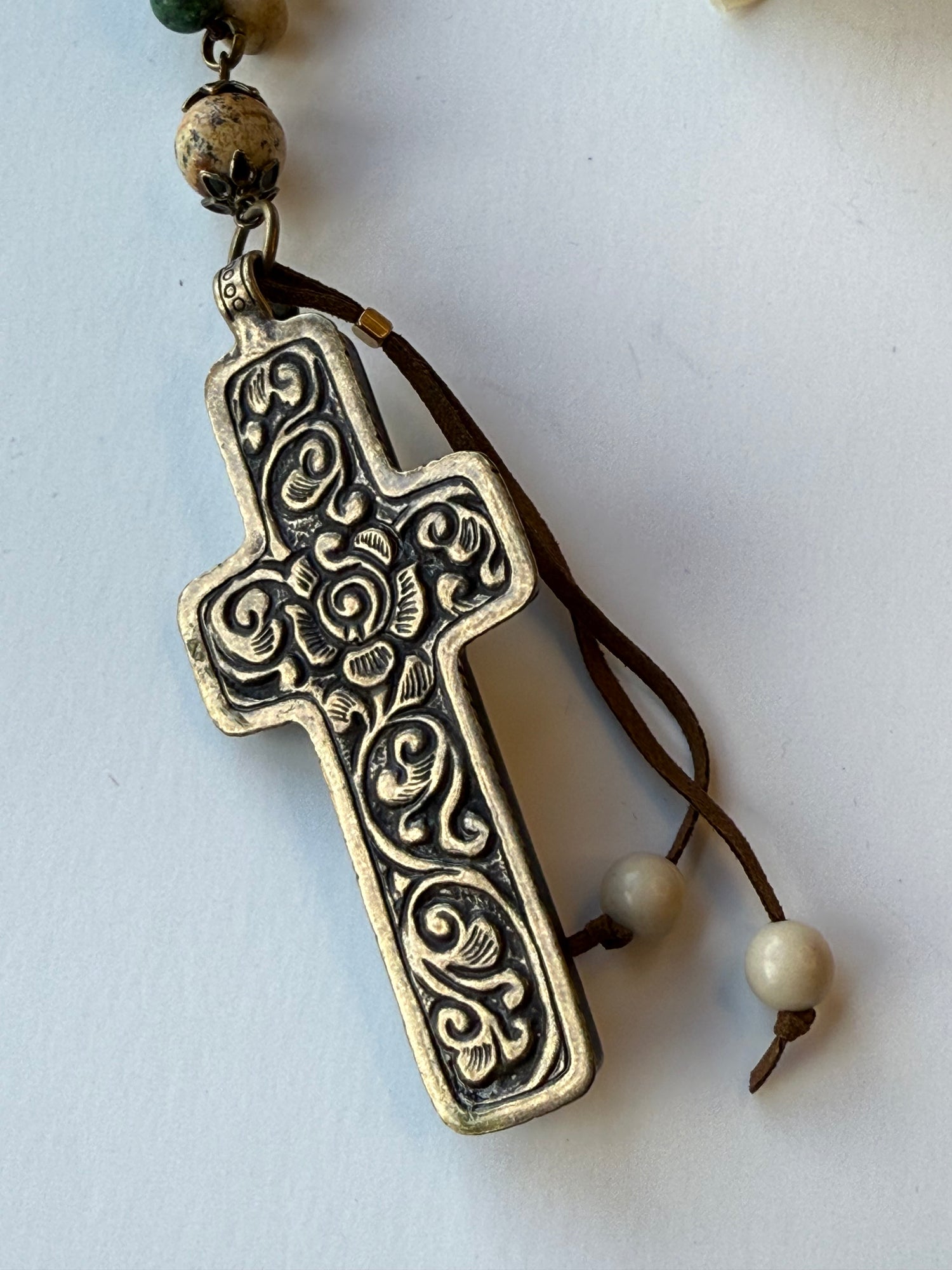 Decorative cross pendant with beads on a white background