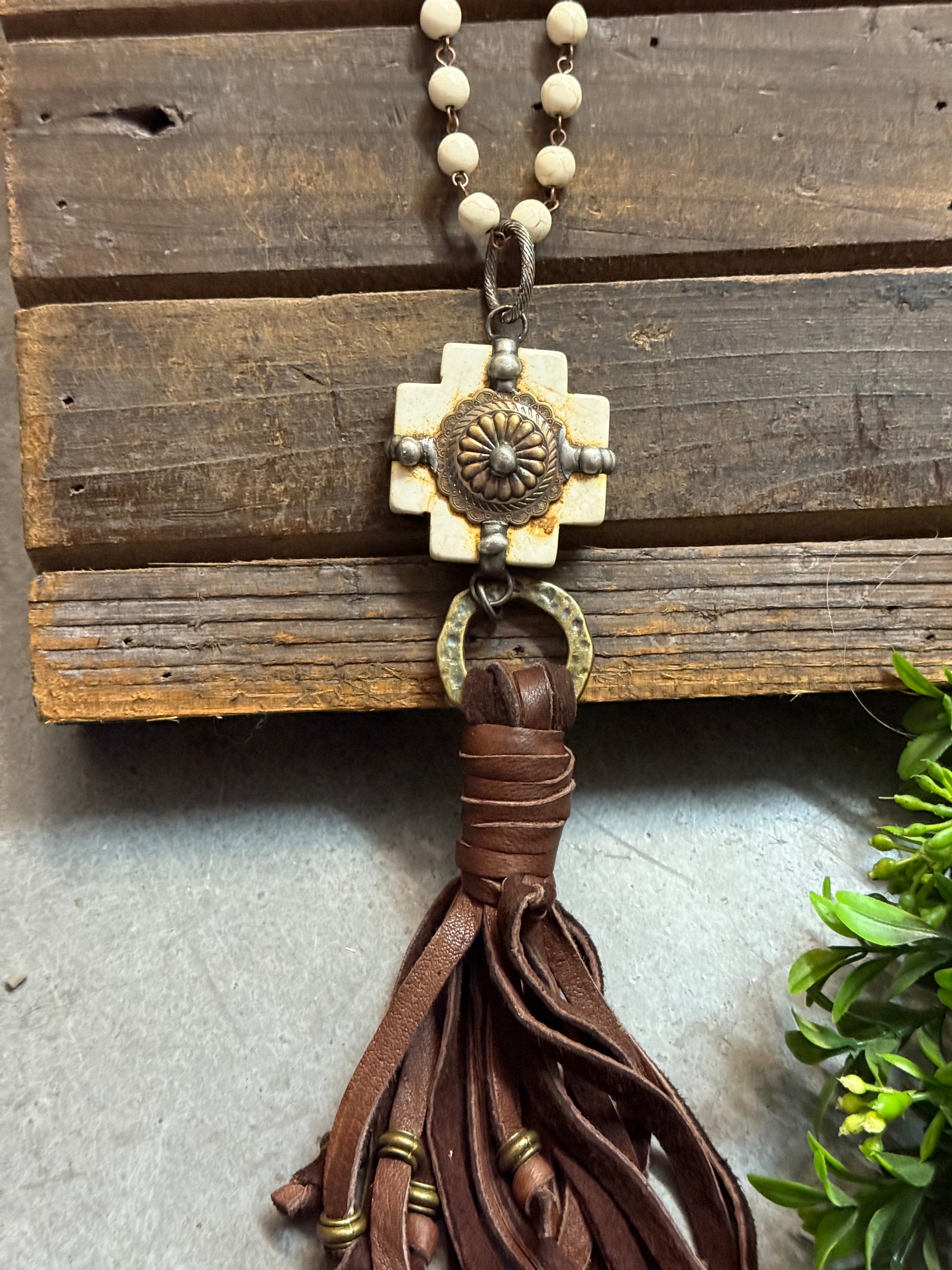Necklace with brown leather tassel and decorative clasp on a wooden surface