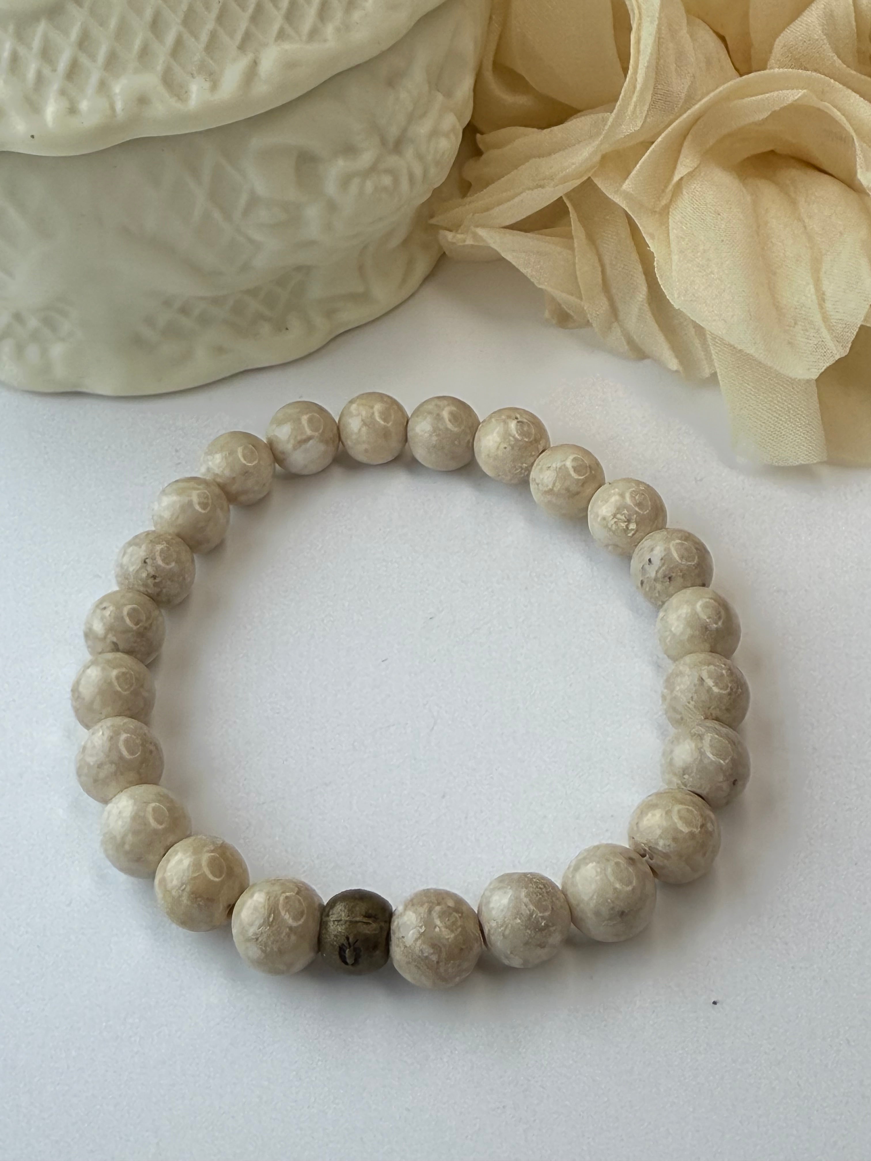 Beige stone bracelet on a white surface with decorative elements