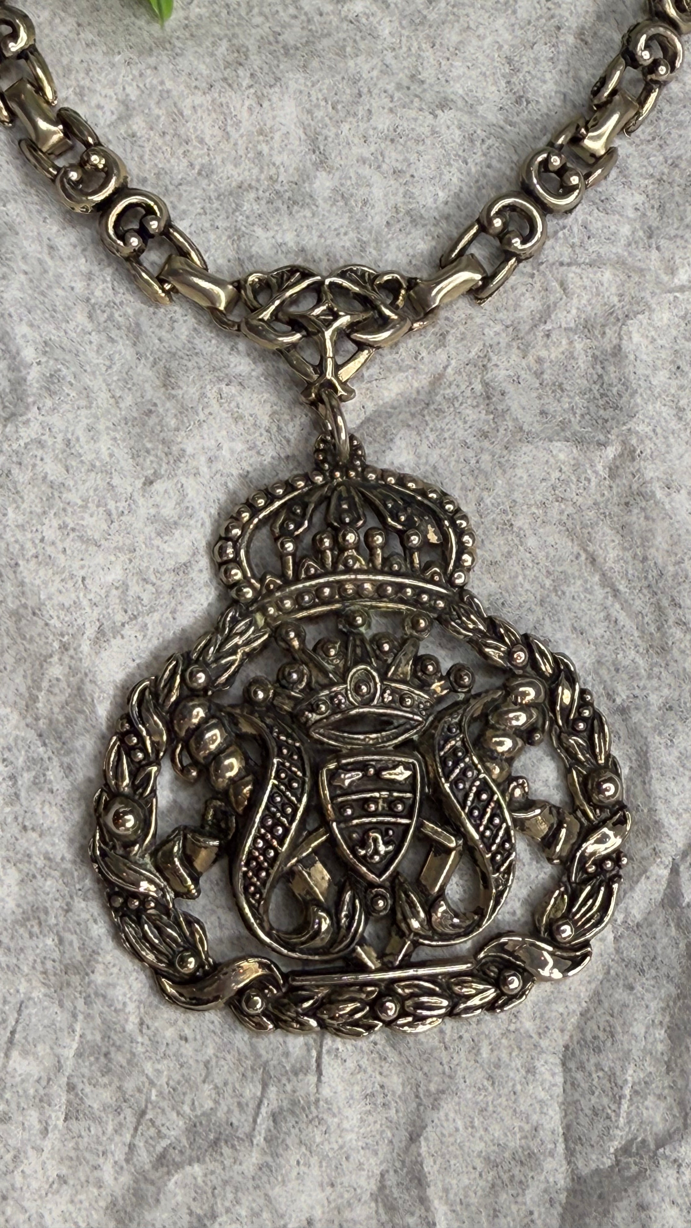 Decorative silver necklace with intricate design on a textured surface