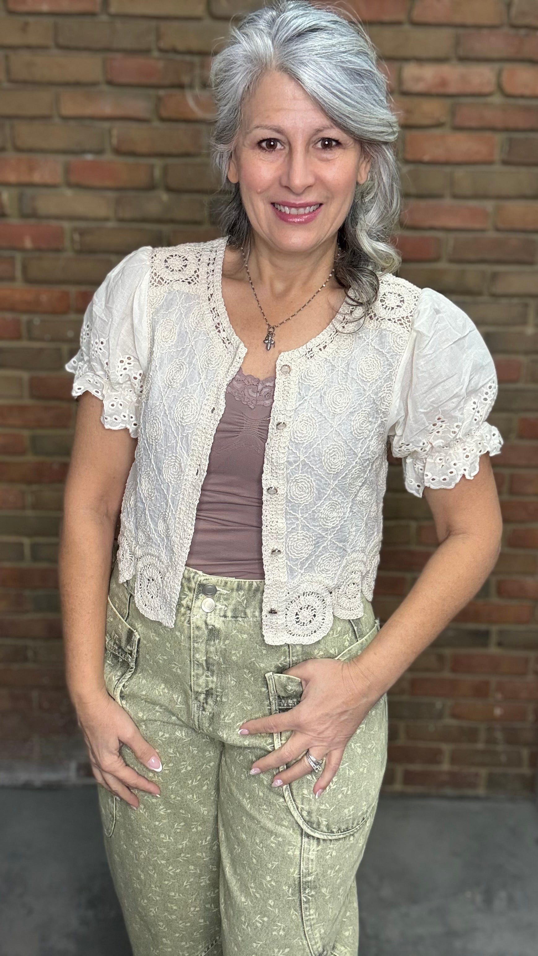 Woman wearing the Crochet Embroidery Button-Up Top and Floral Printed Barrel Pants with a brick wall background
