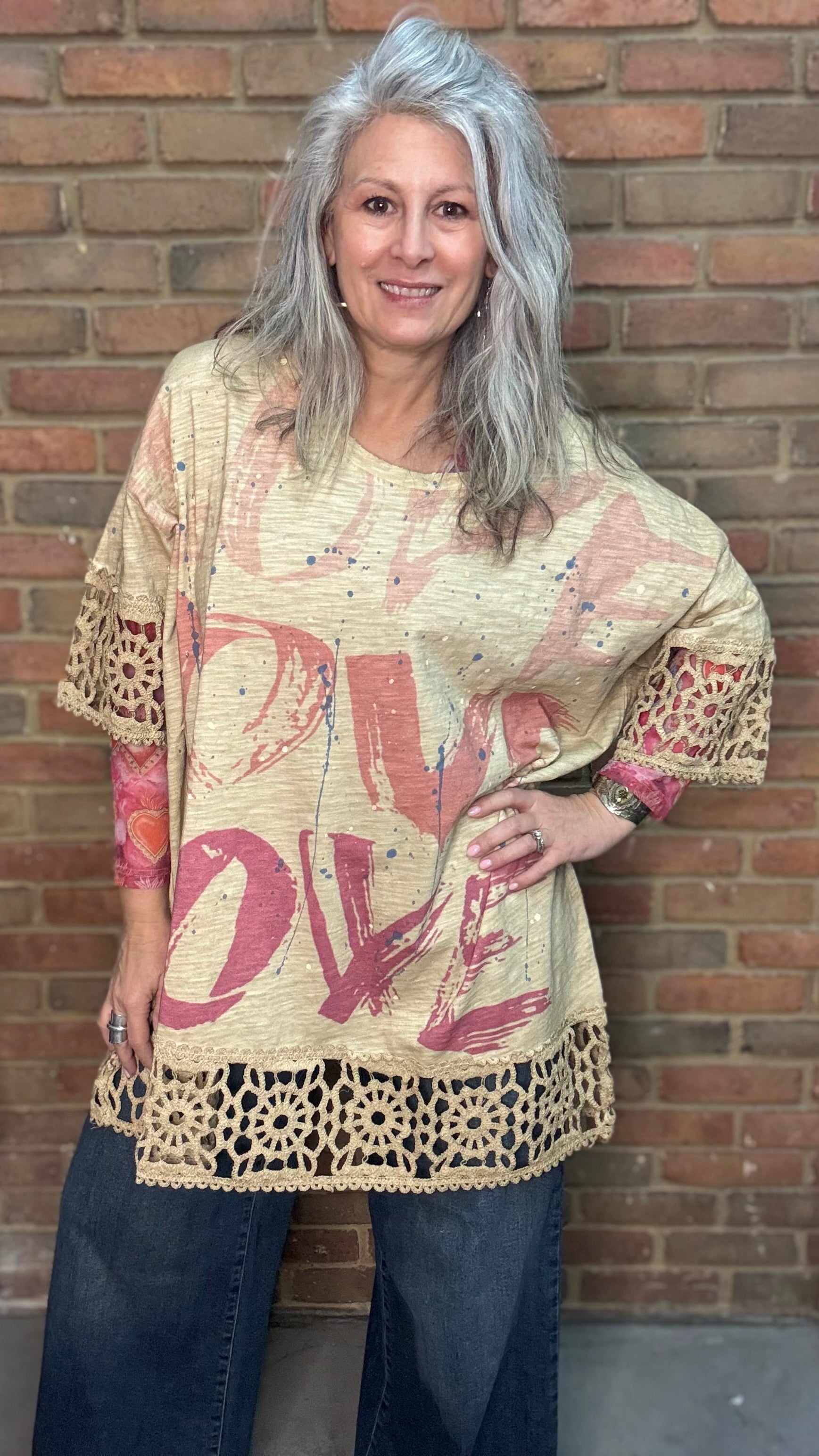 Woman wearing The LOVE top standing against a brick wall.