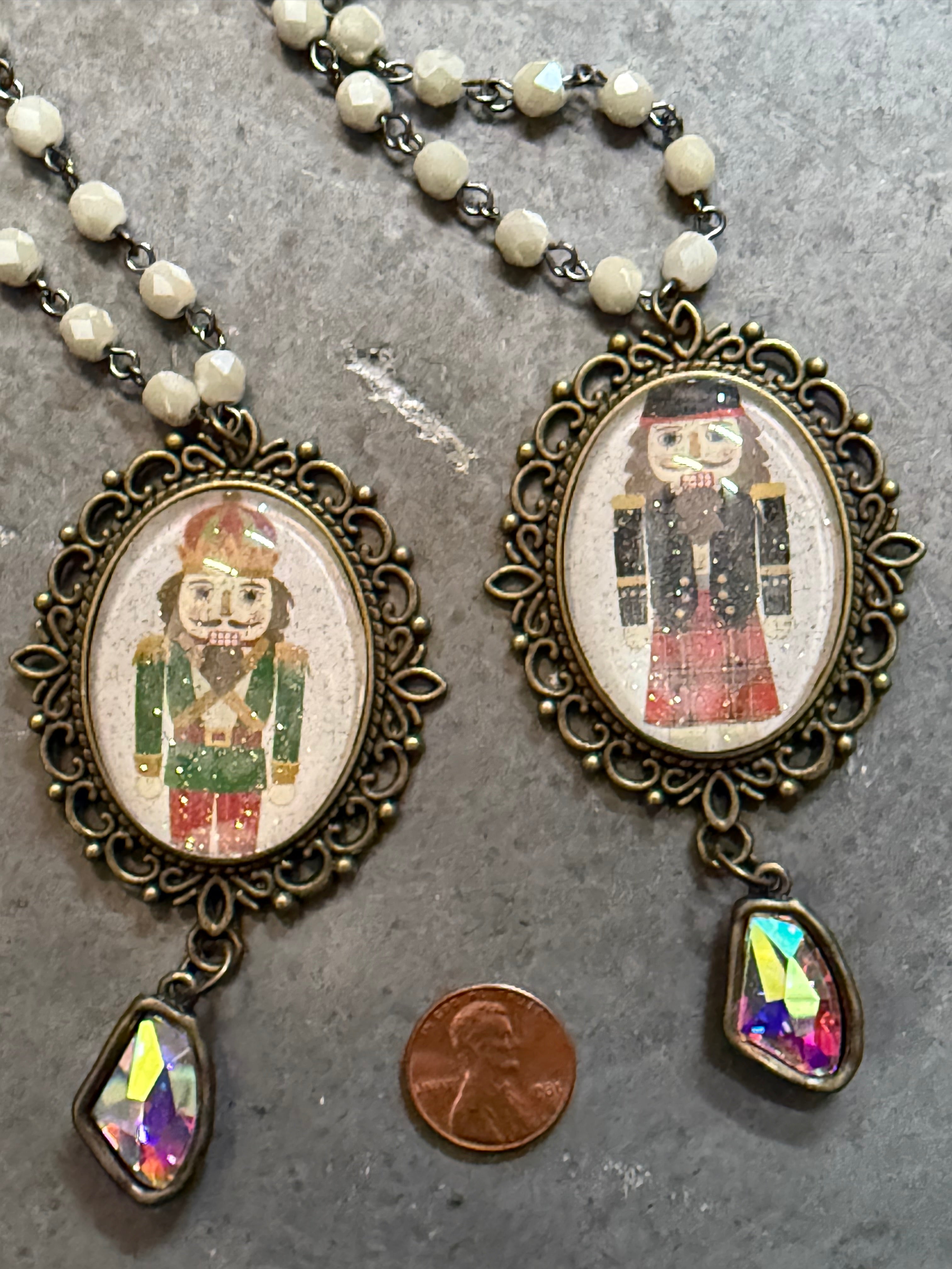Two ornate necklaces with pendant images of a person in a suit on a gray surface.